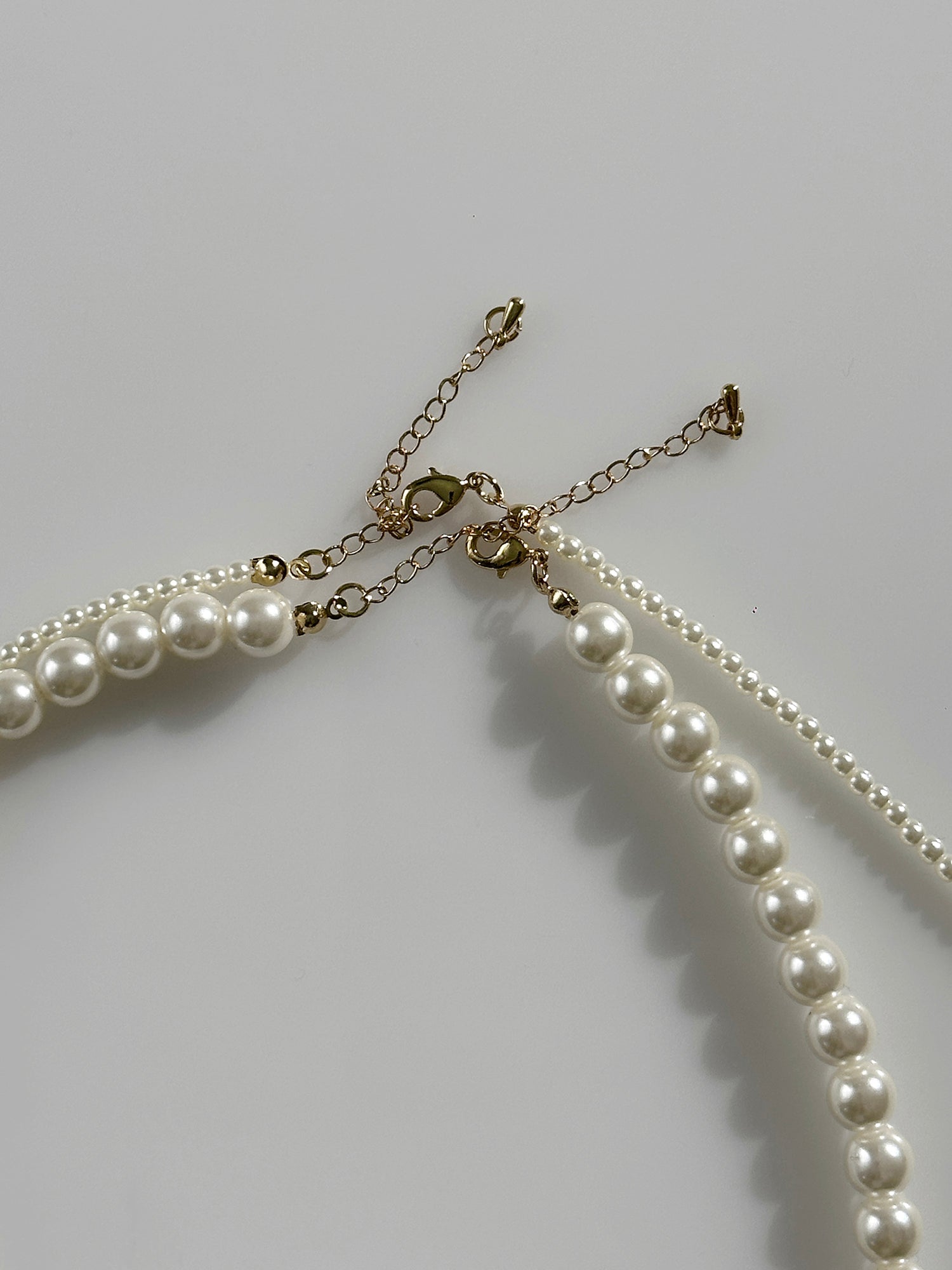 A zoomed-in shot of the long pearl strand necklace showing the hook clasp details of the necklace.