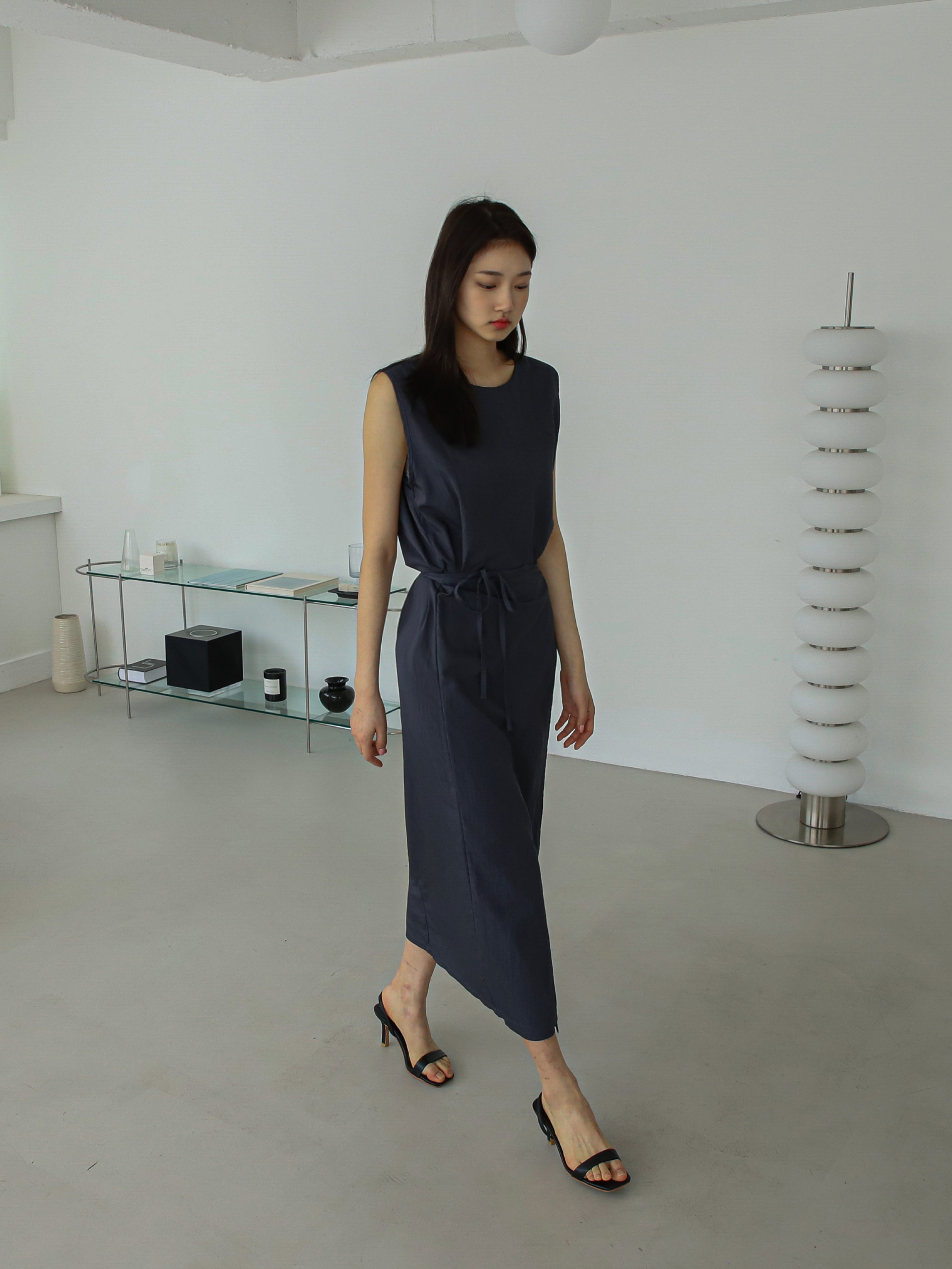 A model walking image wearing a navy maxi dress styled with black heels that shows the fitting of the dress.