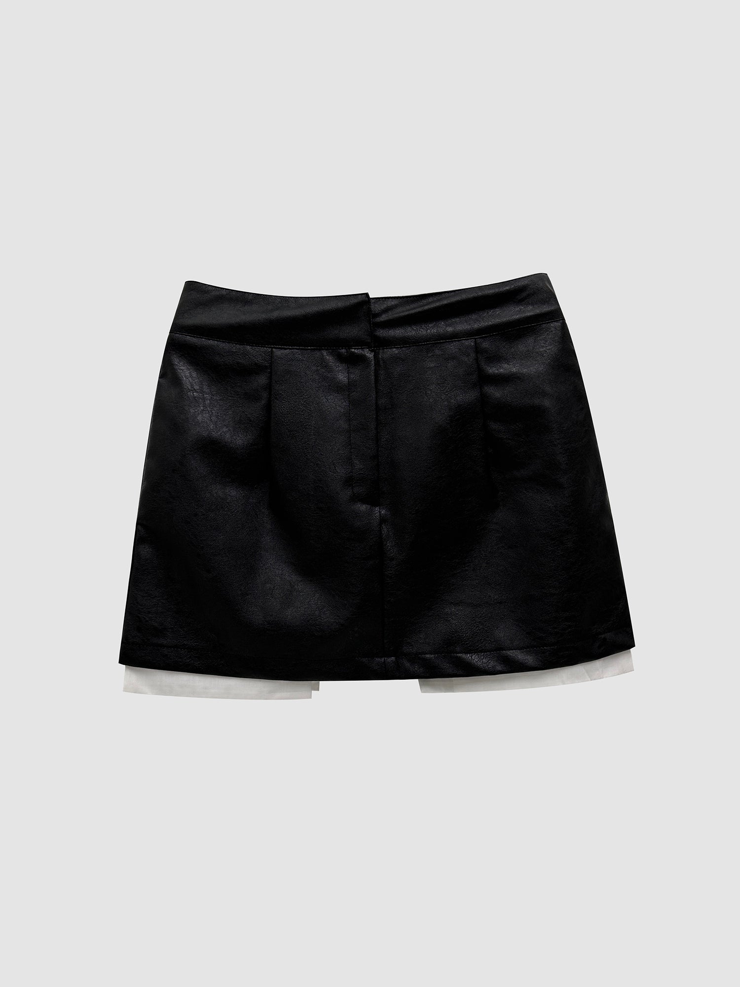 Front detailed view of the black mini leather skirt with gray backdrop to accentuate its front detailed designs.