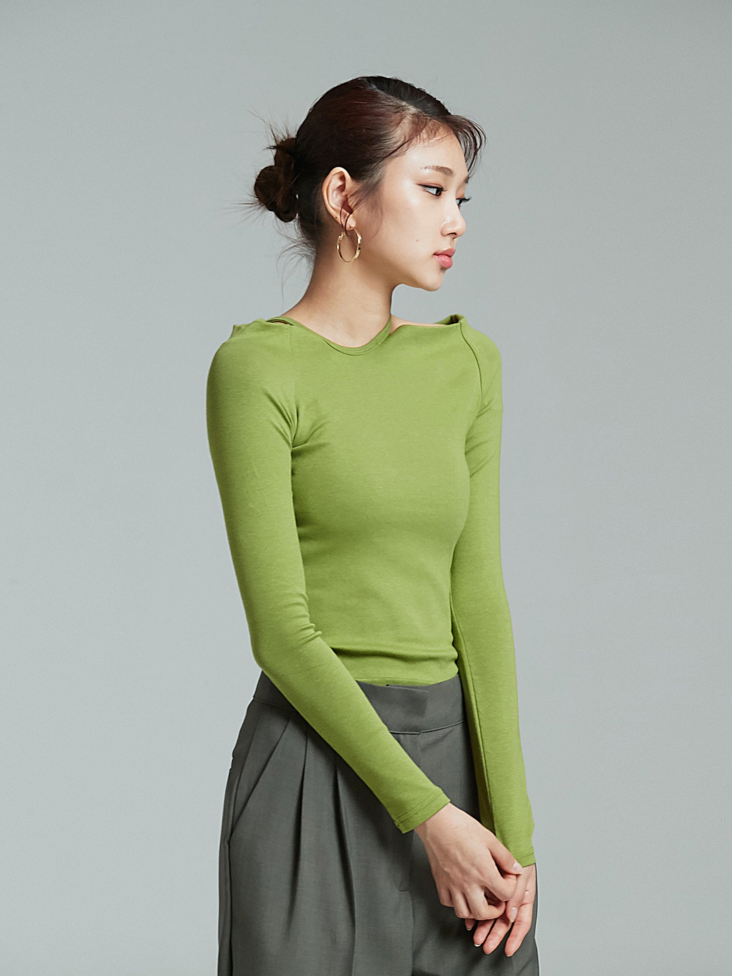 A tilted angle of the model wearing the green open shoulder top showcasing its korean street fashion look.