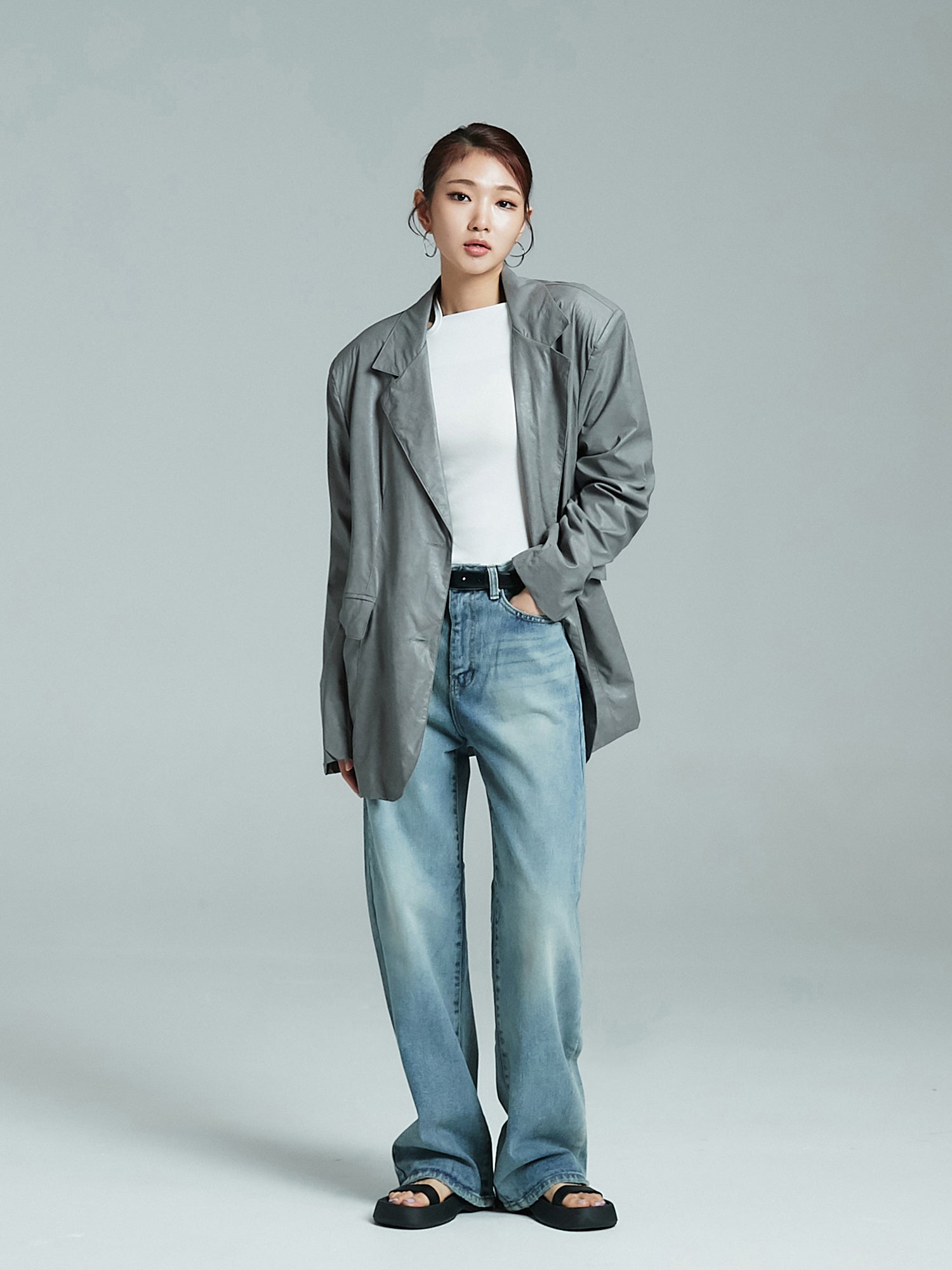 A full-shot of the model flaunting Korean street fashion in an oversized jacket, with one hand casually tucked inside the pocket.