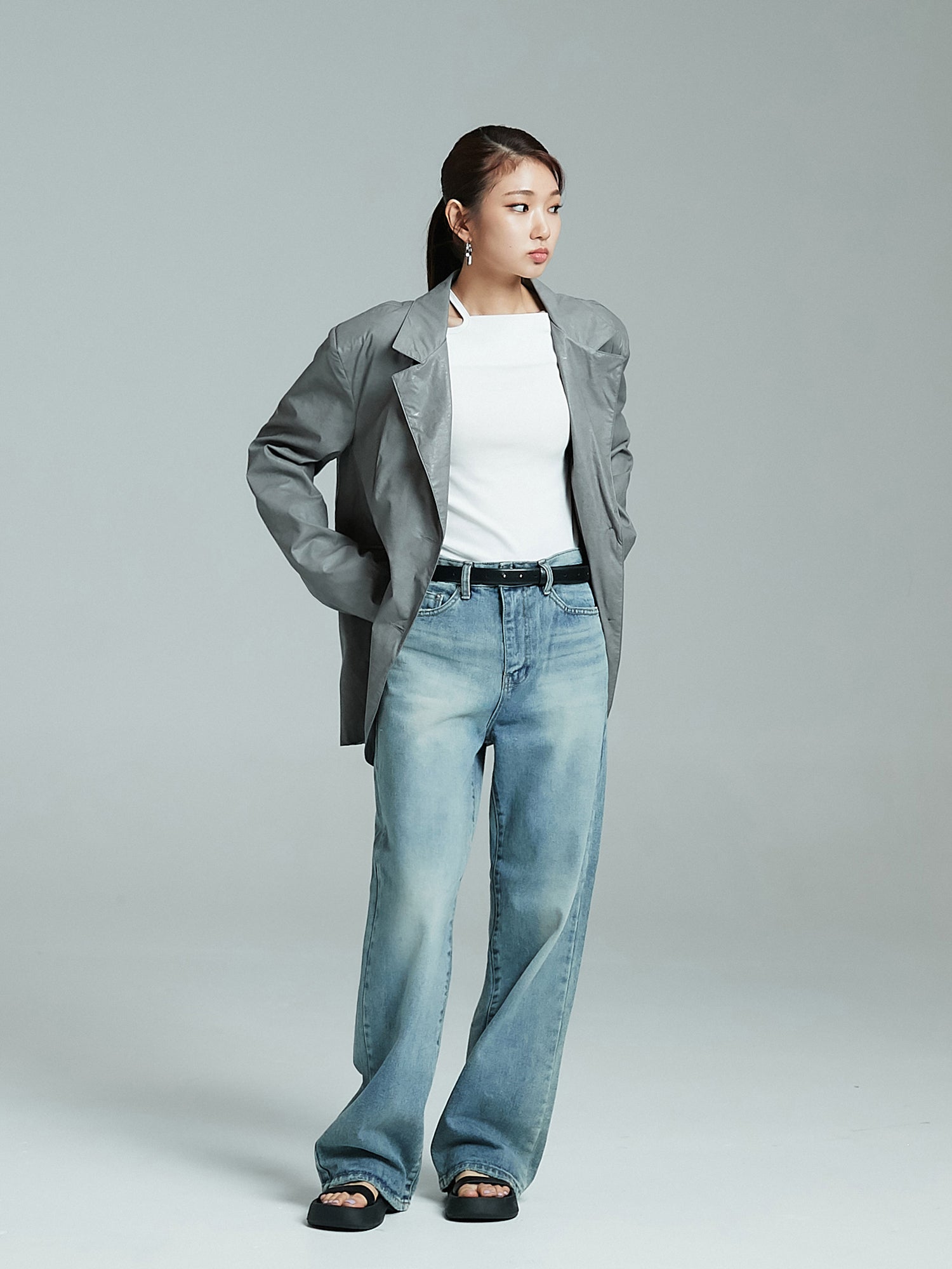 The model is looking to the side while showing off the oversized jacket paired with washed jeans.