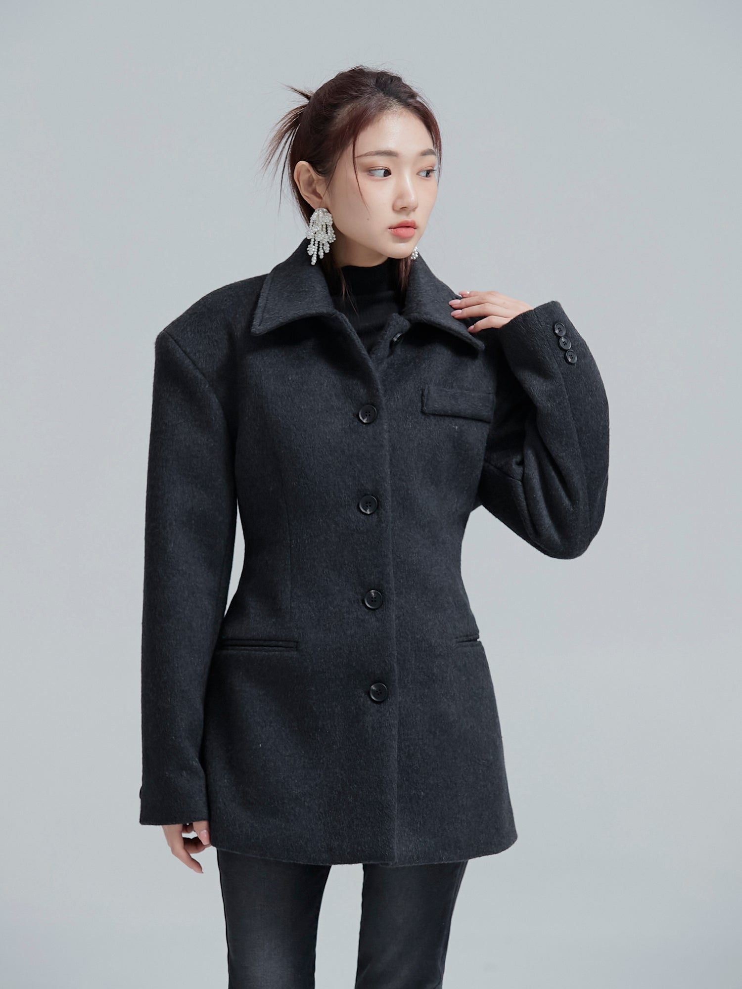 Model posing while wearing the padded fitted coat to highlight its shoulder padded detail.