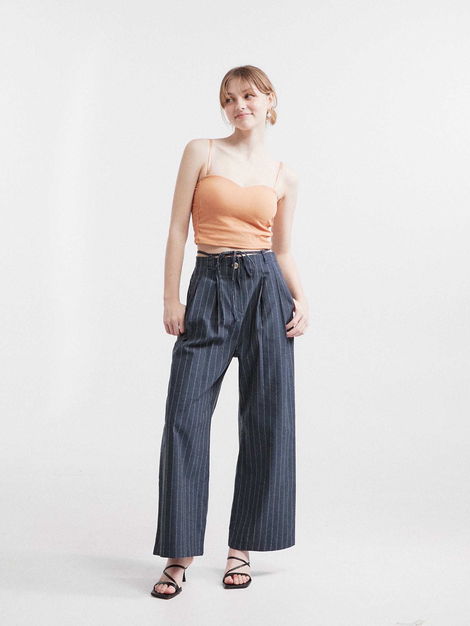 Front view of the model confidently posing in the striped belt-tie trouser.