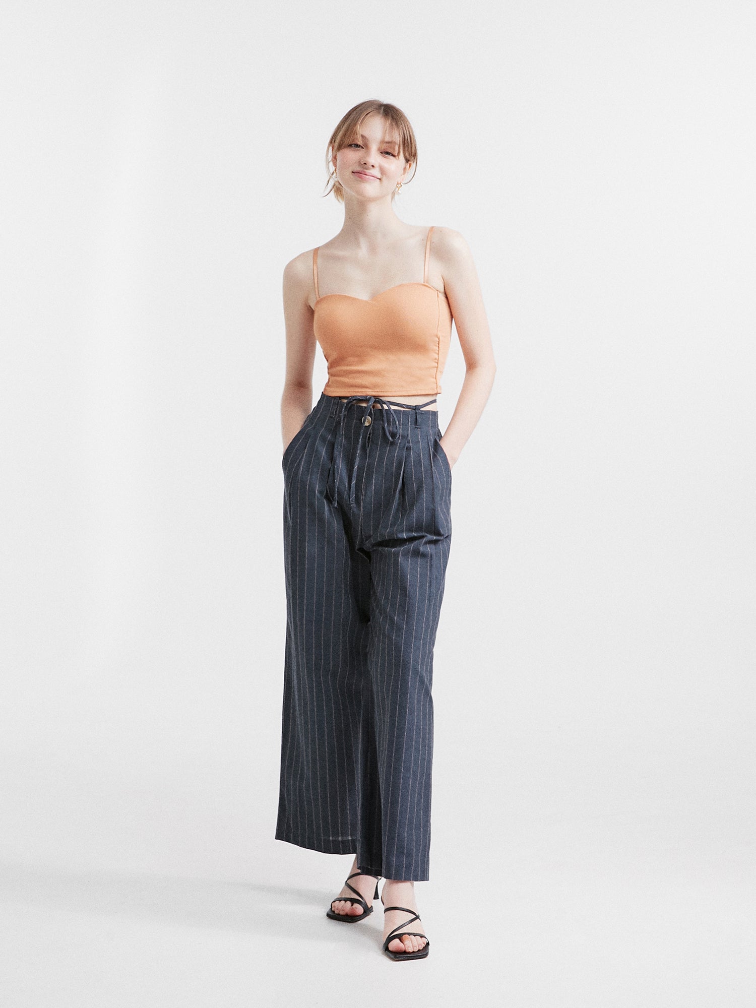 Front view of the model wearing the striped belt-tie trouser matching it with bustier crop top.