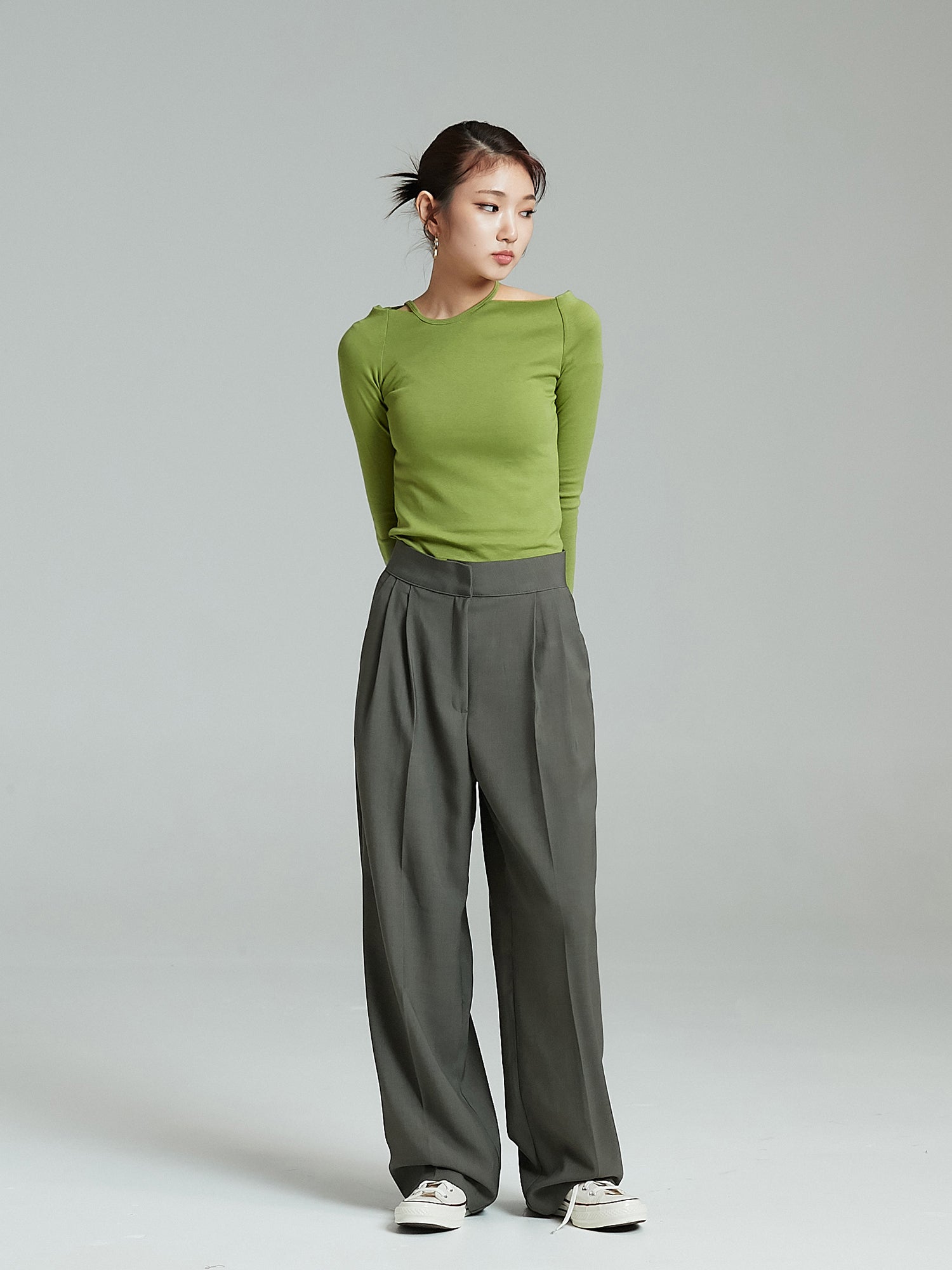 The model is standing still looking to the side while wearing the Pintuck Wide Leg Trouser showcasing the korean street fashion vibe.