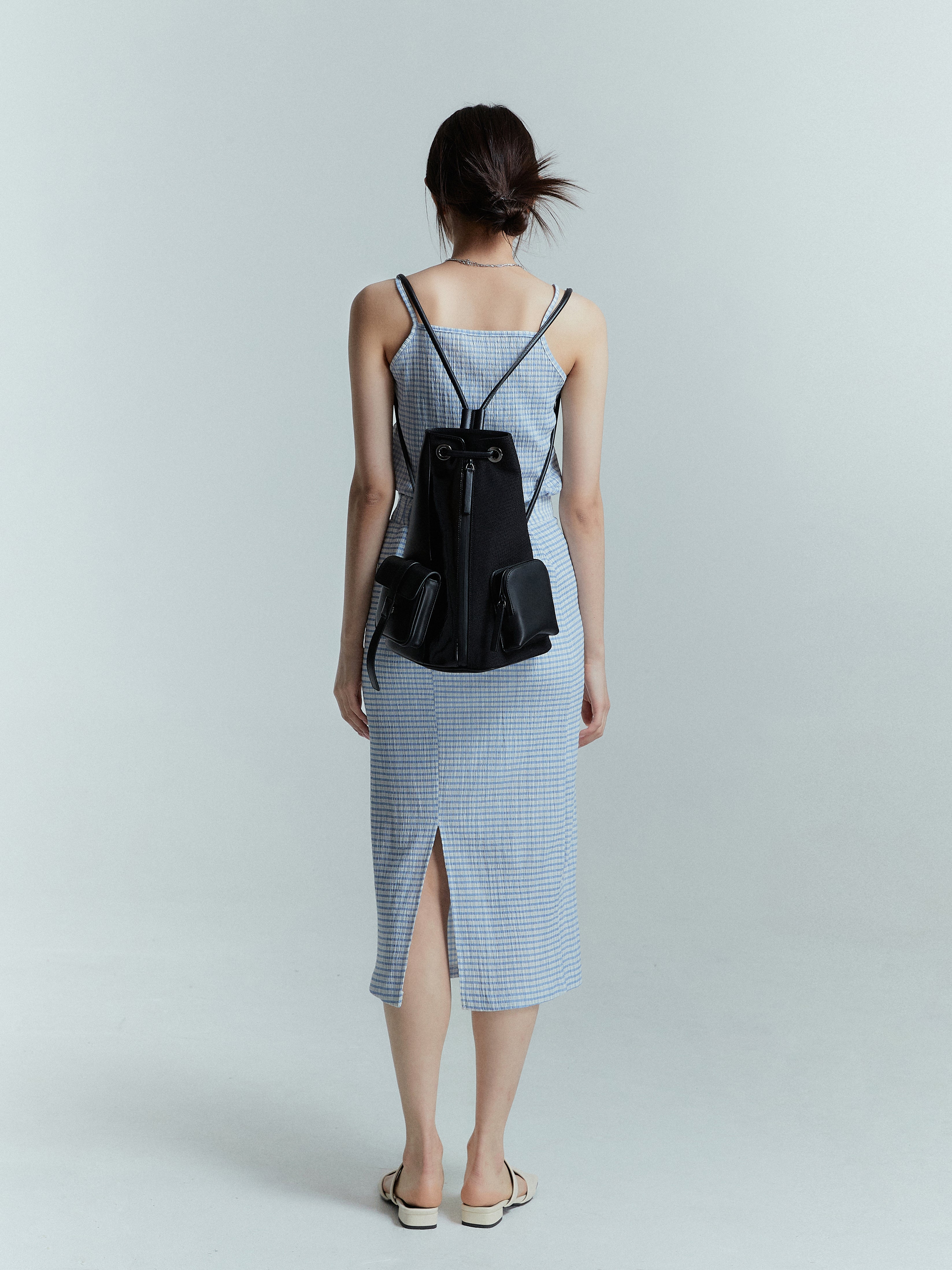 A back side of a model with blue plaid midi skirt showcasing the slit cut design on the back.