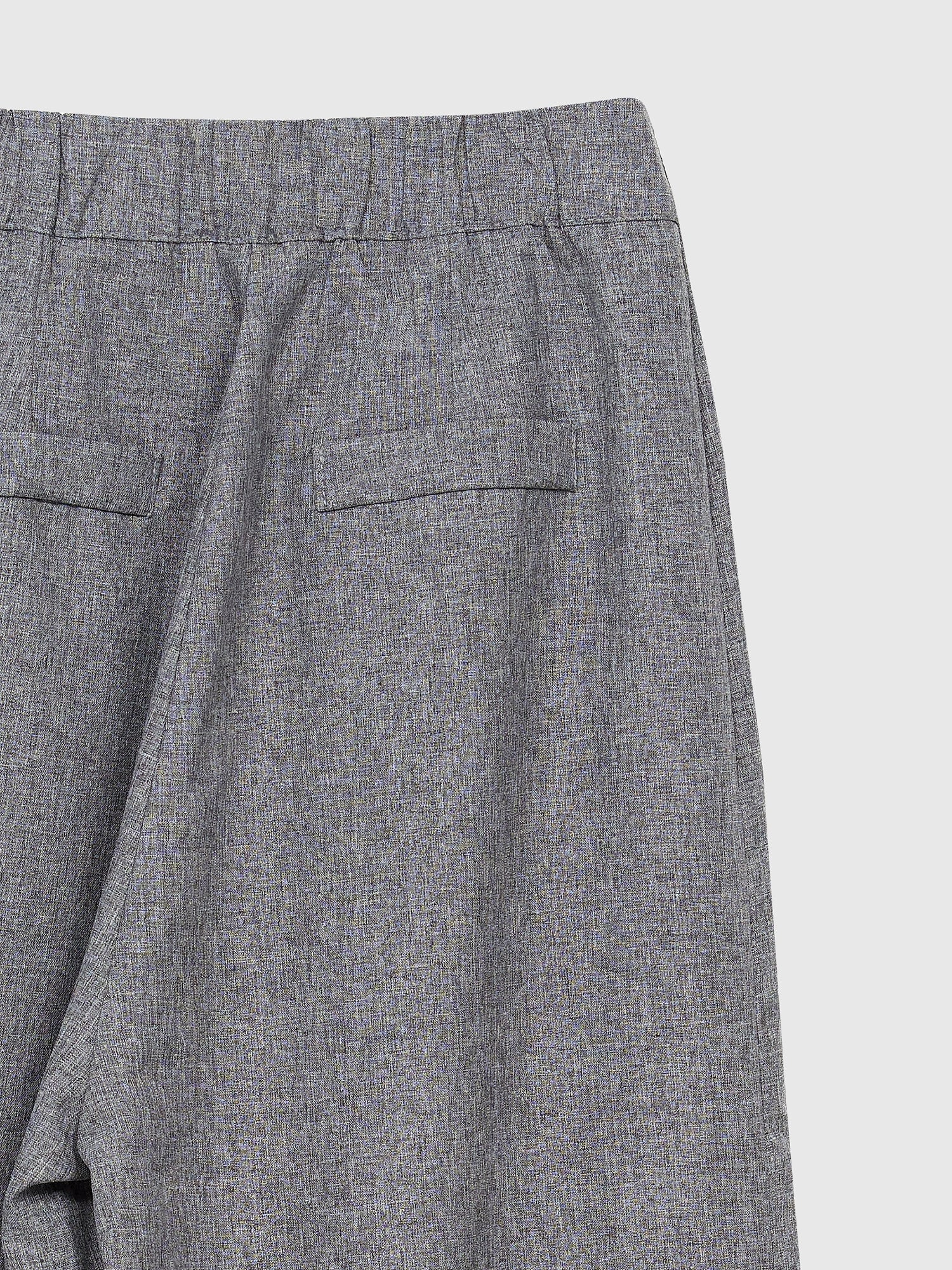 Zoomed-in back detailed view of the pleated-detail trouser highlighting the back pockets and elastic waist detail of the trouser.