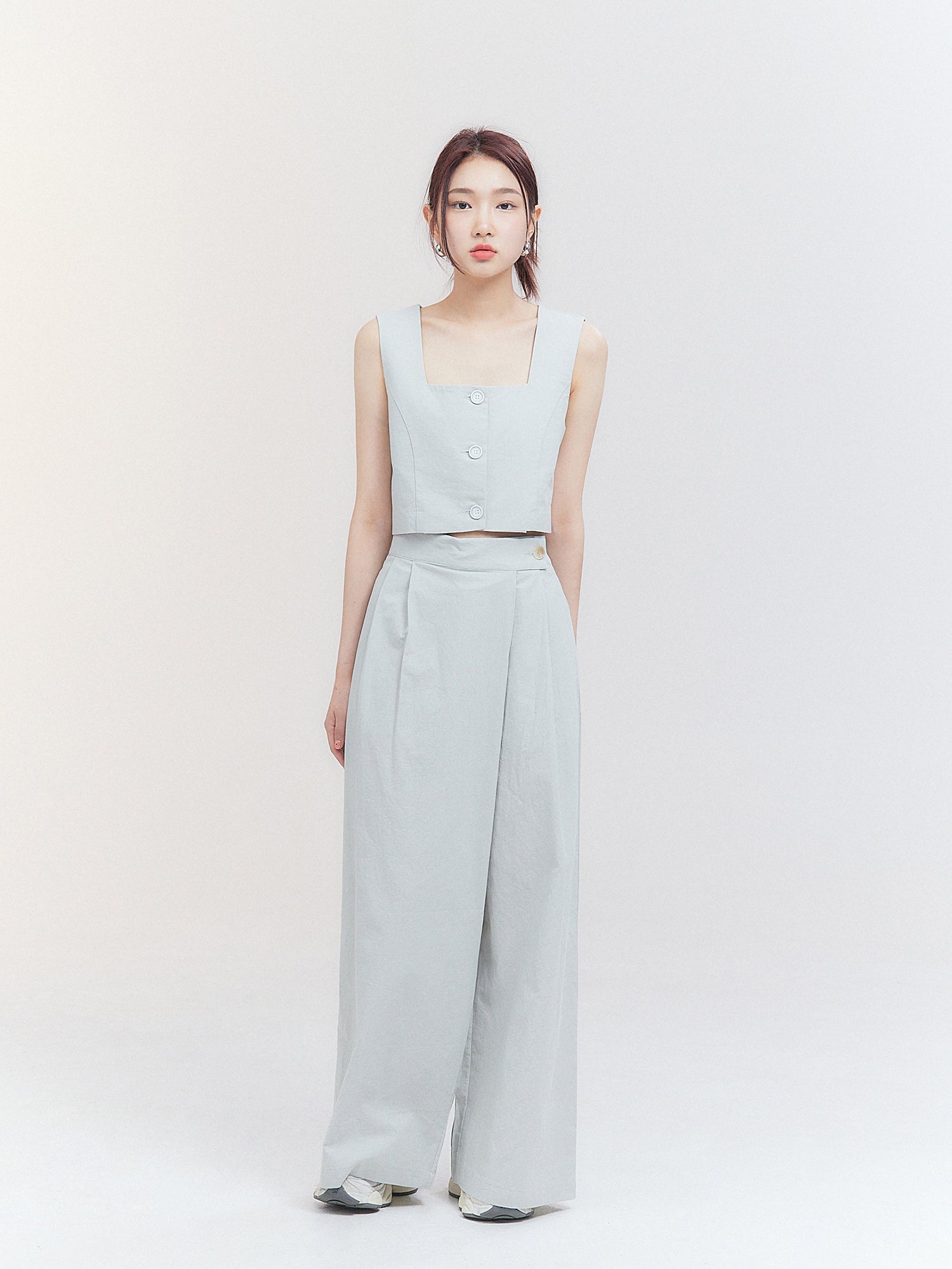 A front view of the model wearing the pleated slit skirt pants, showcasing its contemporary fashion design and style.