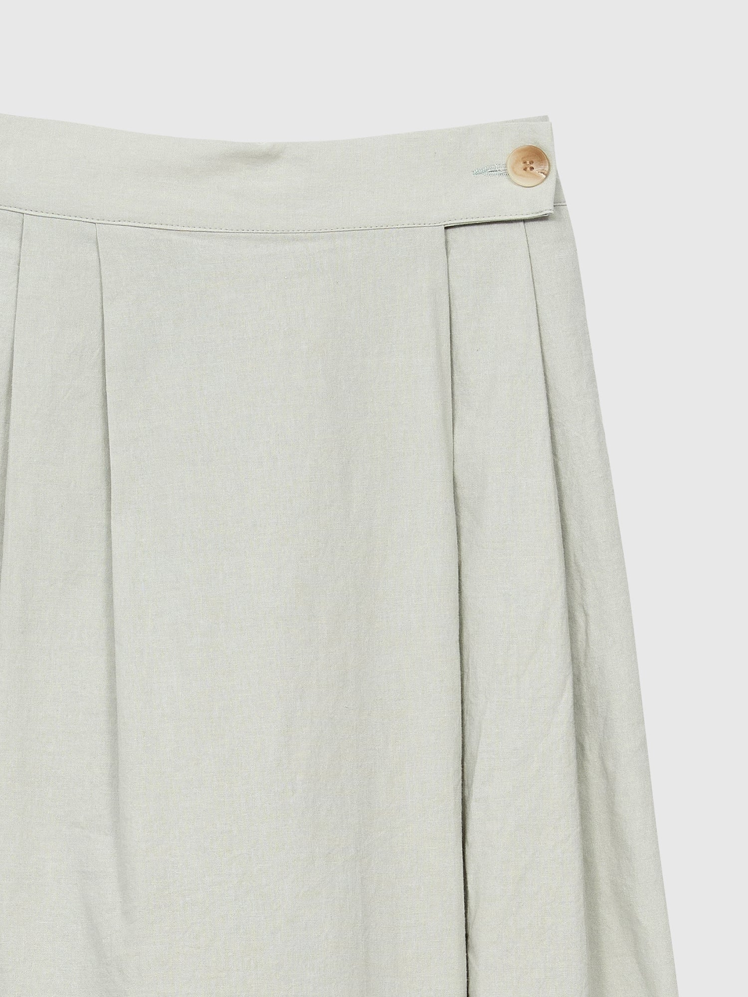 The zoomed-in detail of the Pleated Slit-cut Midi Skirt showing the front button fastening and pleated details of the skirt.