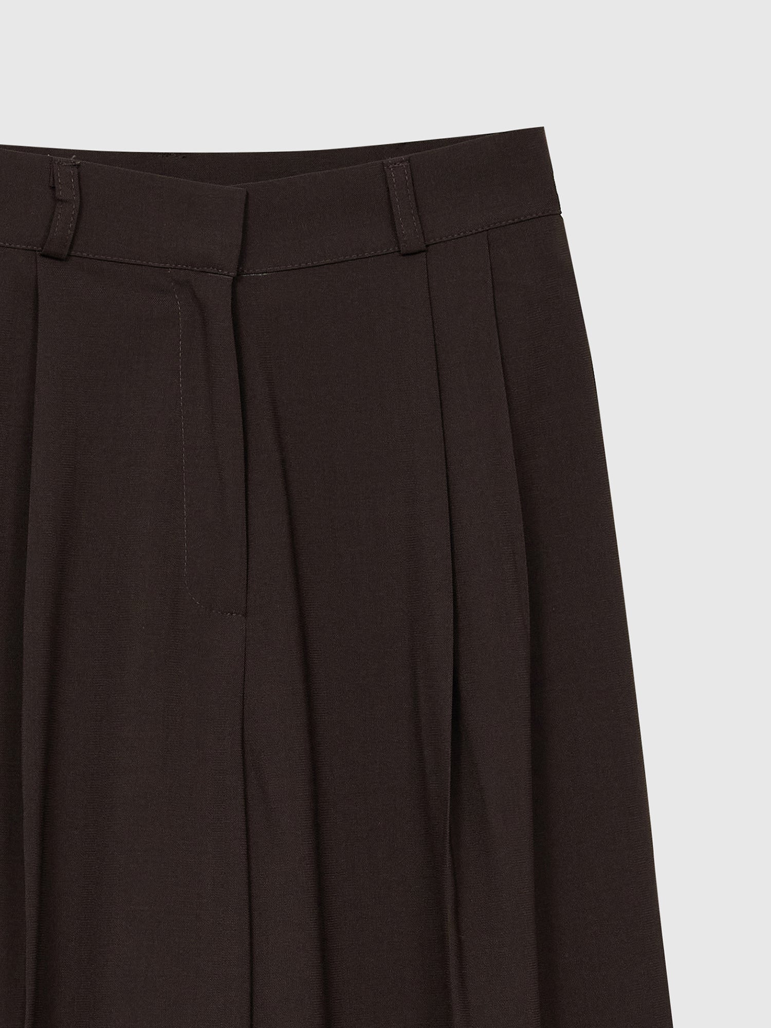 A focused view of the pleated pants highlighting its pleats and belted design details.