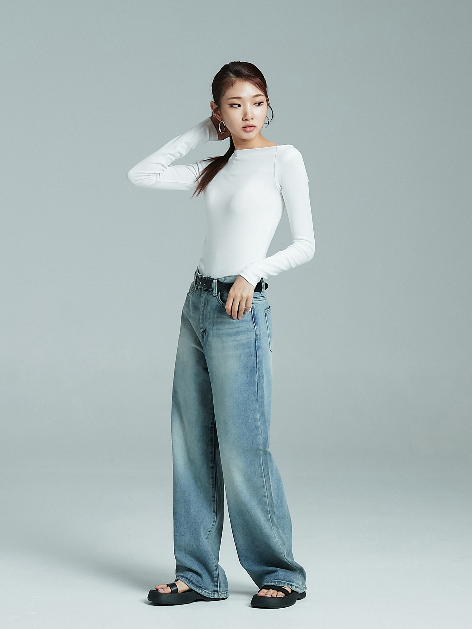 A tilted angle of the model wearing the relaxed wash jeans paired with cut out long-sleeves tee.