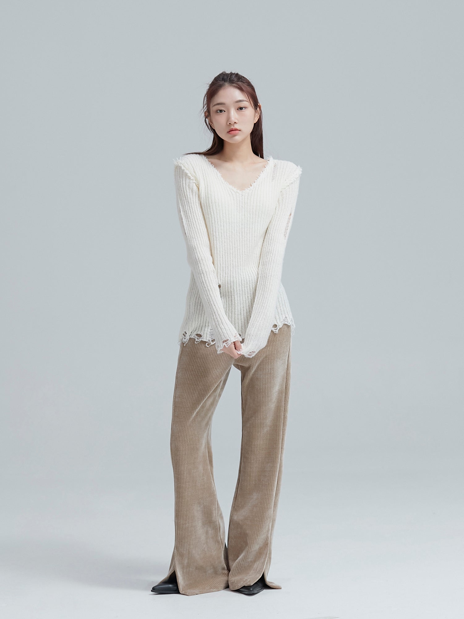 A complete view of the model striking a pose in a ripped sweater paired with corduroy split wide pants, embodying the charm of Korean aesthetic outfits.