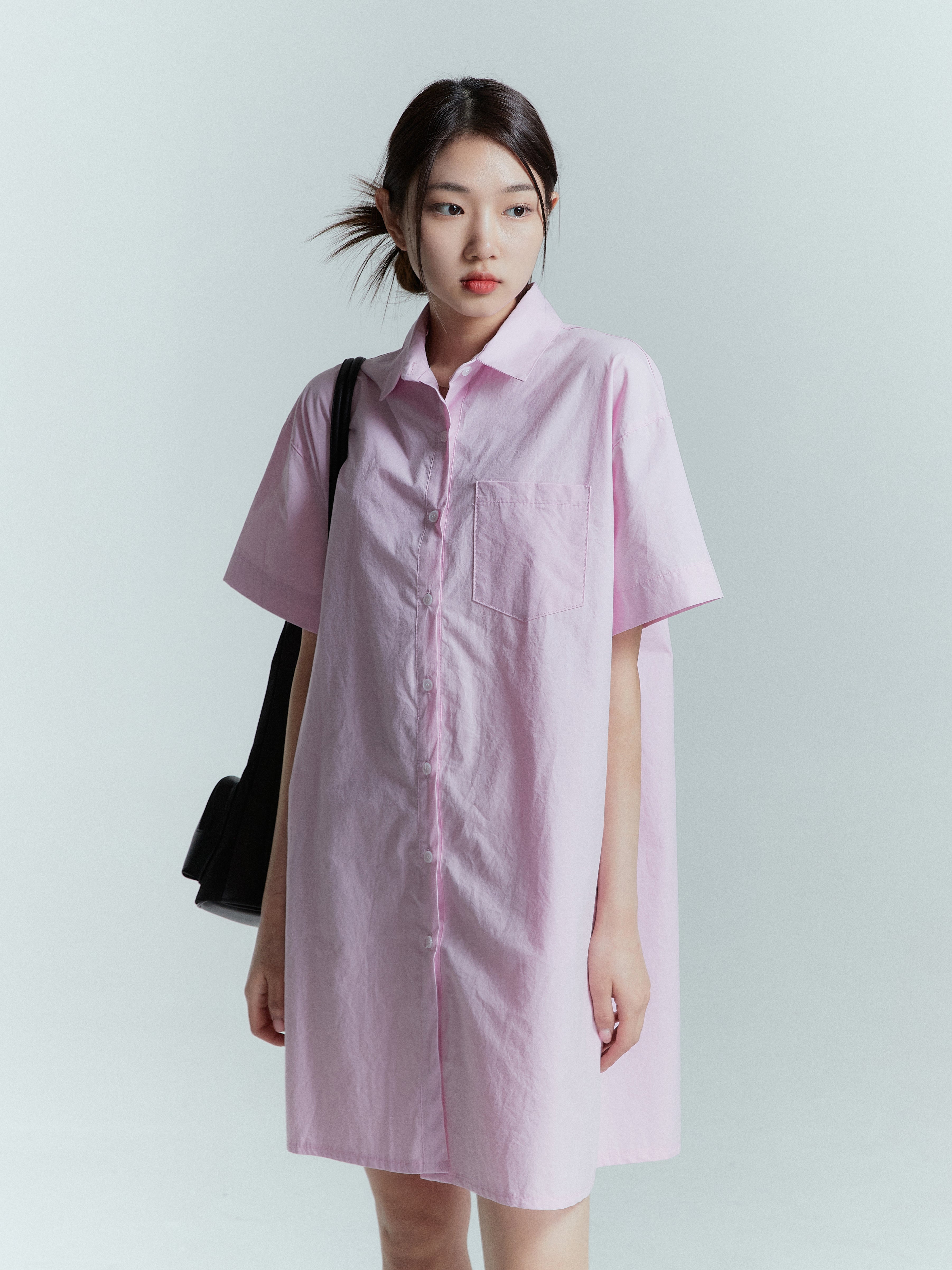 In a medium shot, the model showcases the pink shirt dress with a subtle angle, captivating attention and highlighting its beauty.