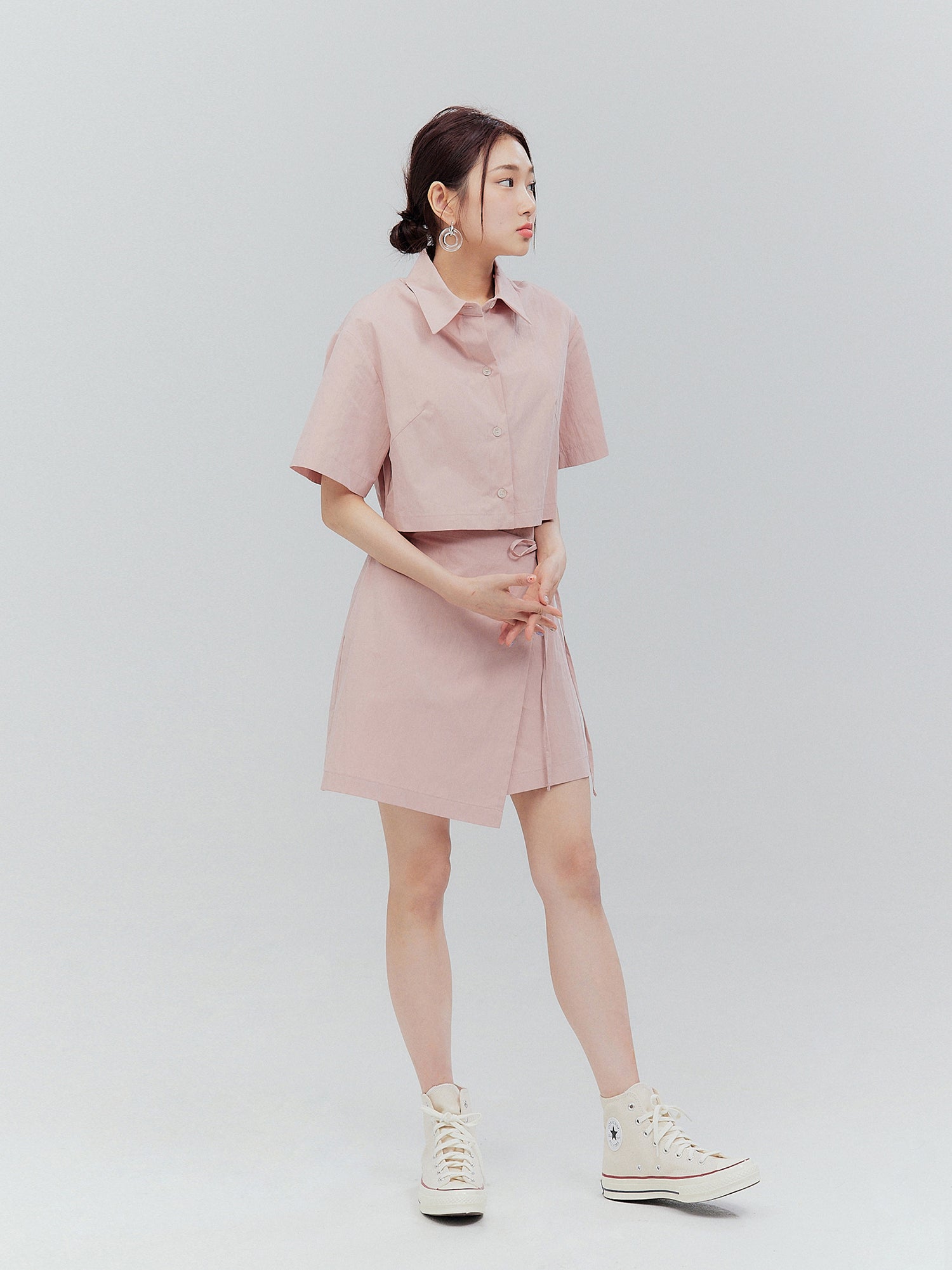 Experience the allure of Korean aesthetic outfits with a captivating full-body image of the model in a tilted view, gracefully showcasing the pink shirt dress.