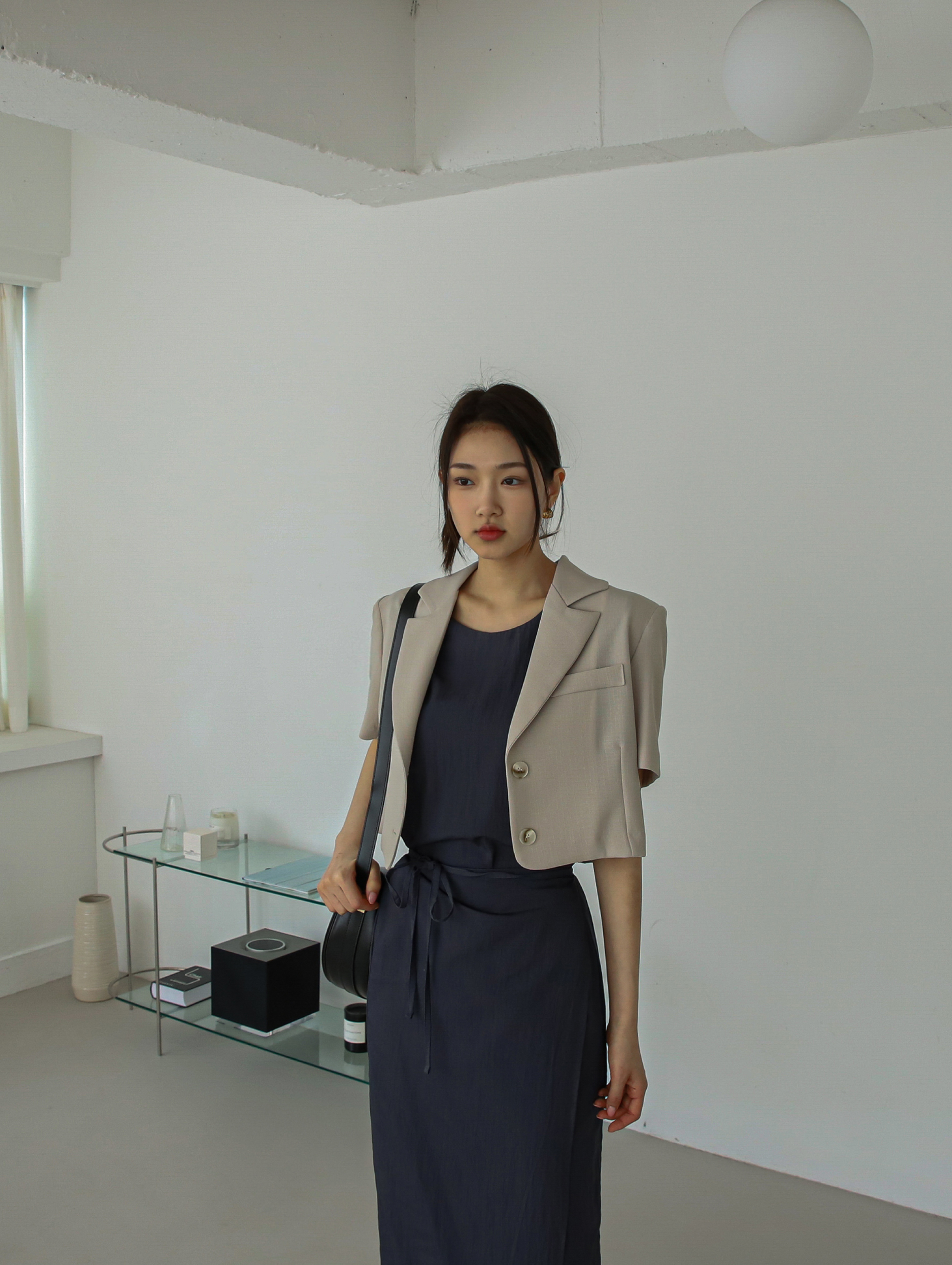 A tilted angle of a model wearing the light beige short-sleeve blazer pairing it with the stylish maxi wrap dress.