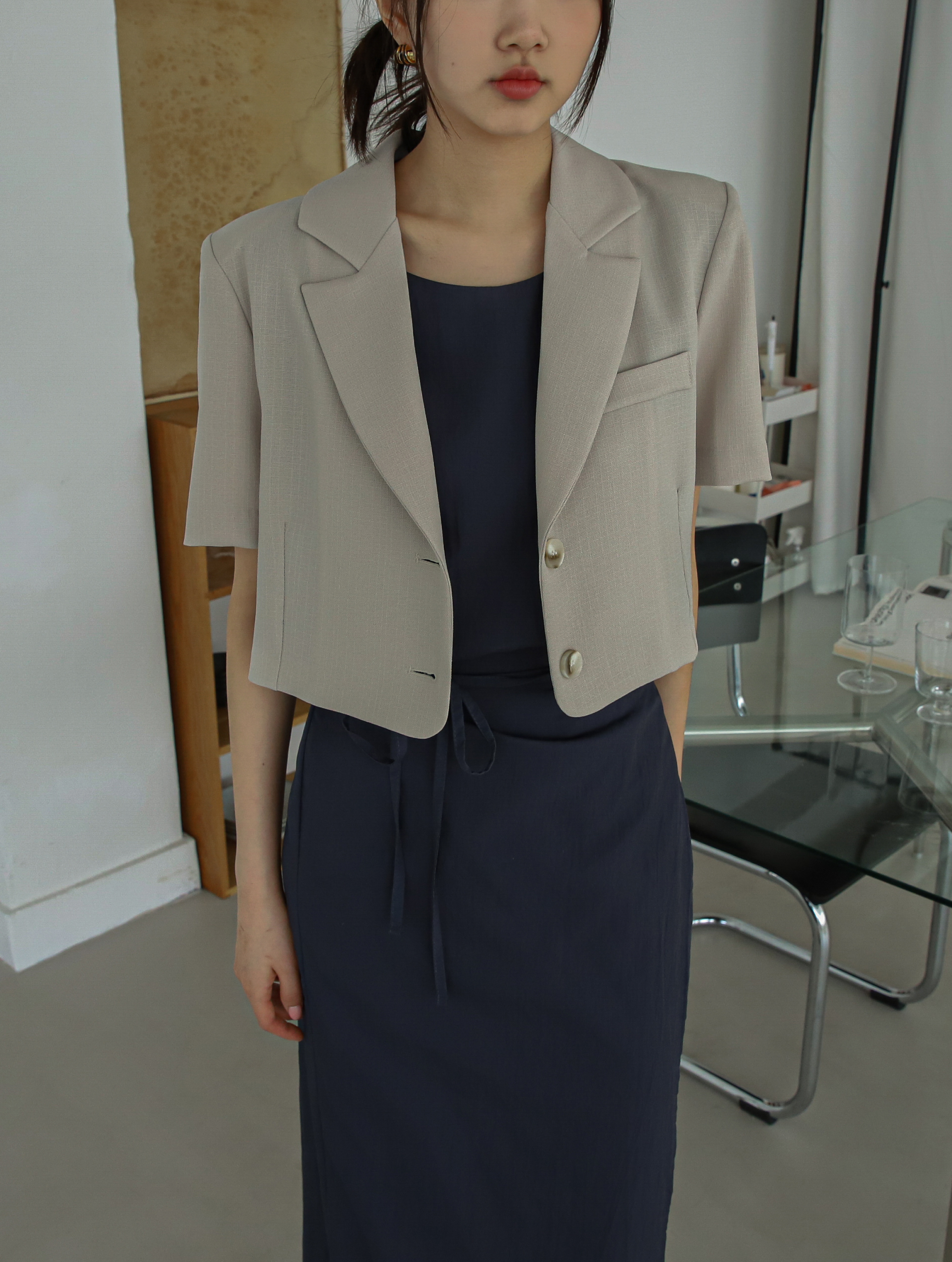 A close-up shot of a model wearing the short-sleeve blazer showcasing the closer look of the blazer.