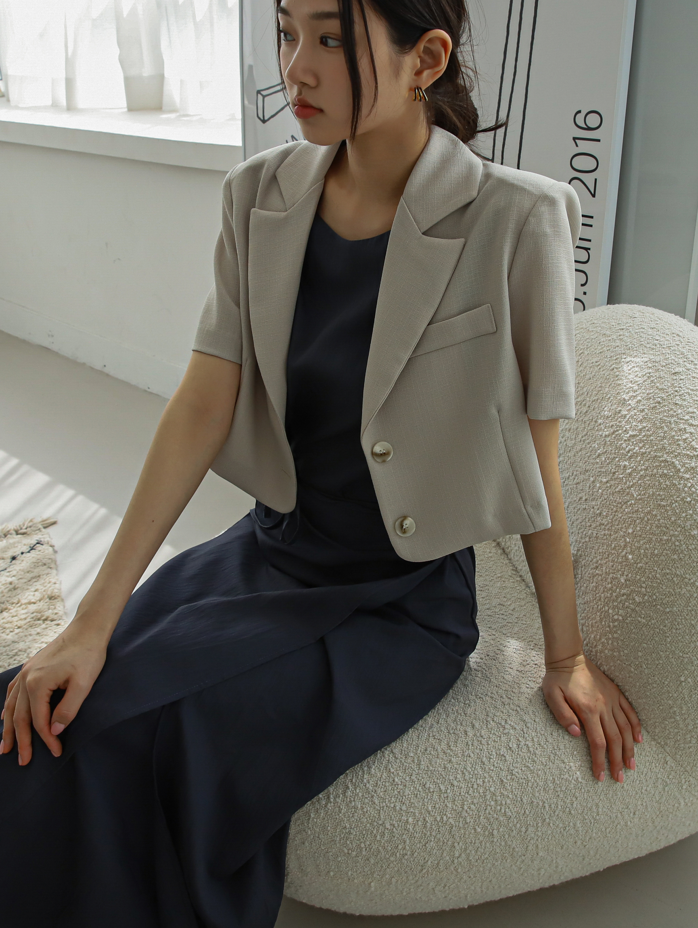 Model in a seated position wearing the short-sleeve blazer.