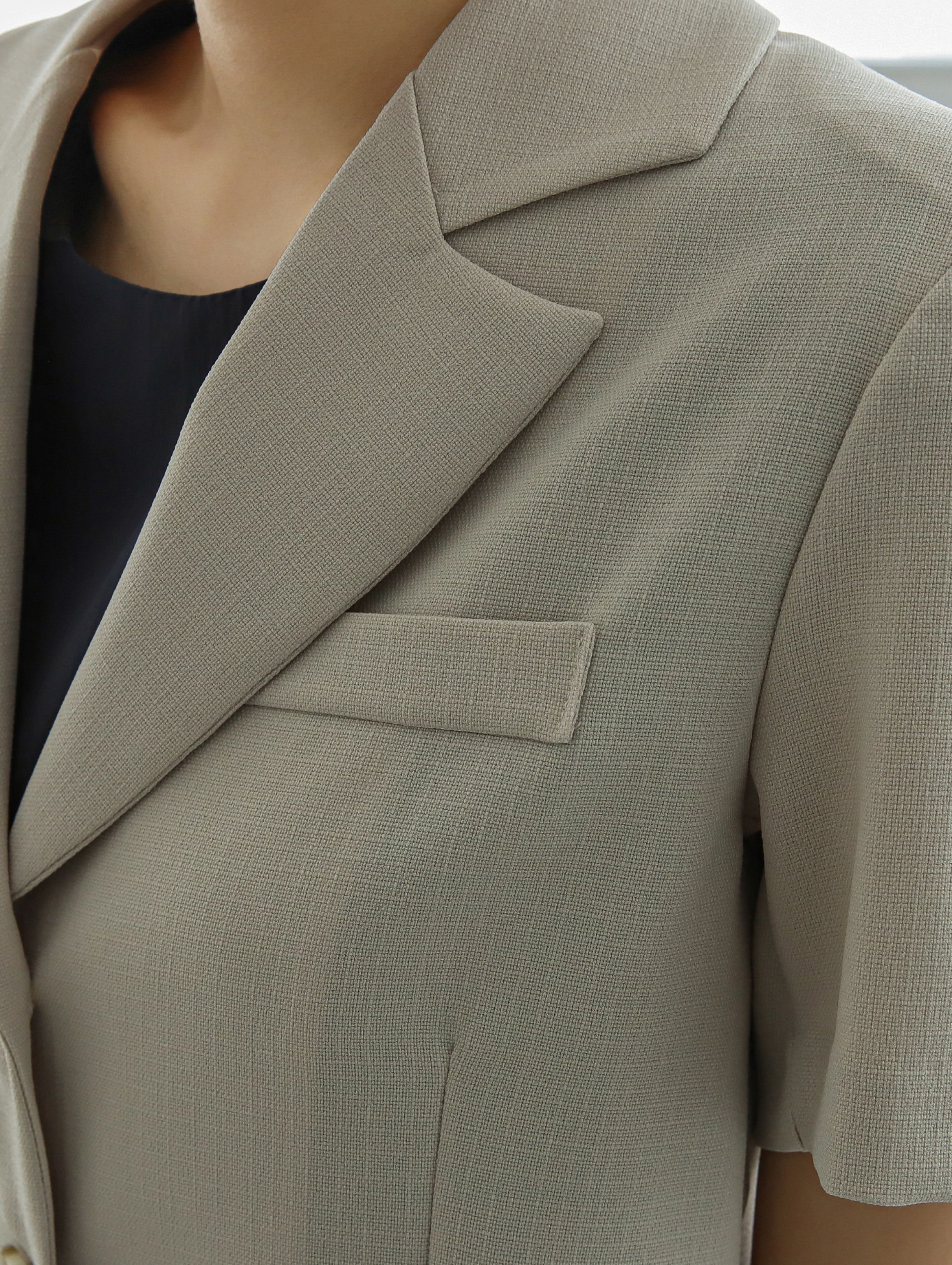 Zoomed-in image of the short-sleeves blazer showing the intricate detail of the fabric texture and the lapel collar design.