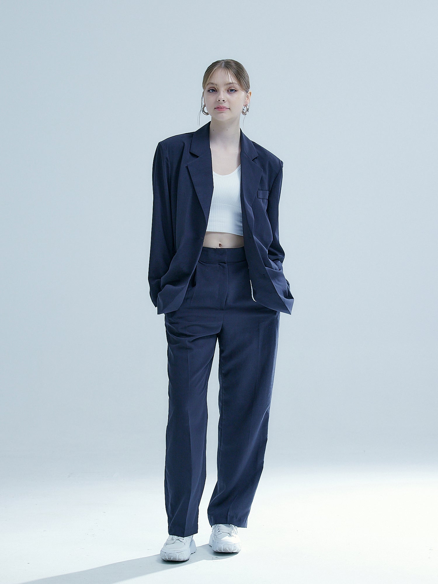 Showcase the front view of the model in Korean street fashion, wearing the charcoal shoulder-padded blazer paired impeccably with trouser pants.