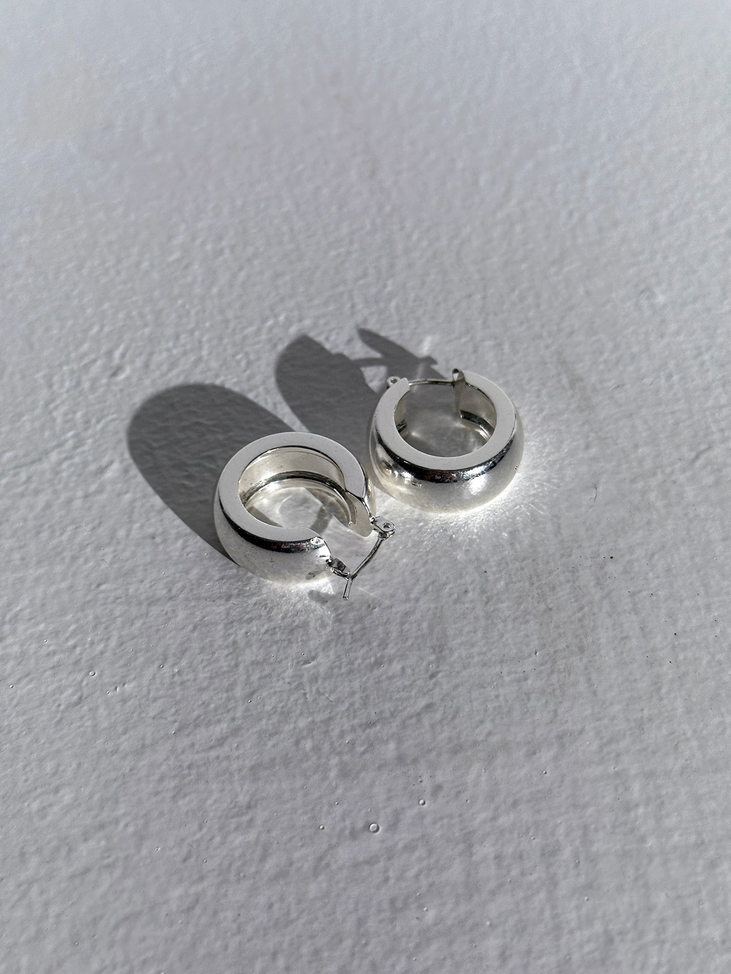 Product detailed image of the silver circle dangle earrings displaying the design of the earrings.