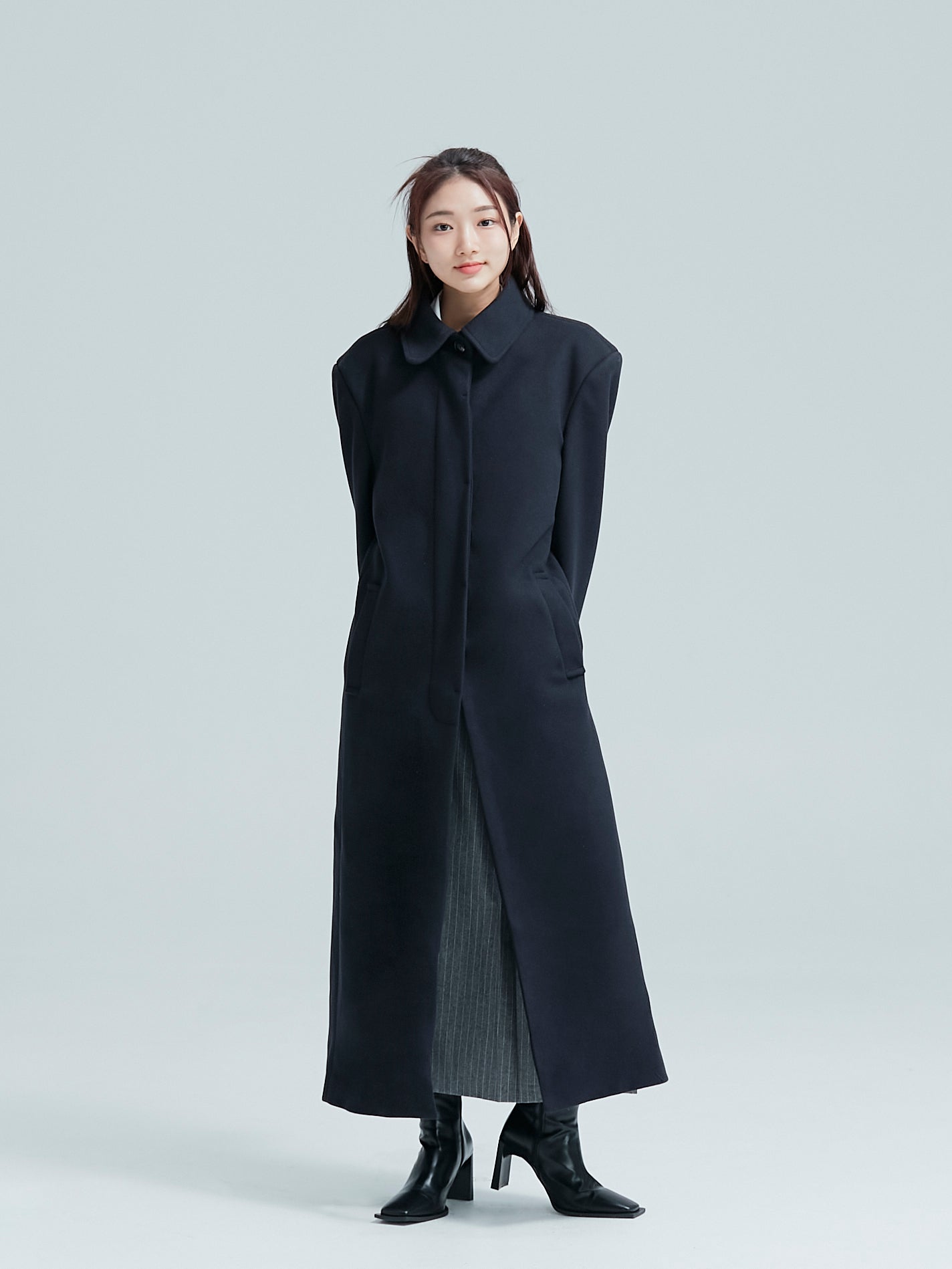 A complete view of the model striking a pose in a single-breasted overcoat to exhibit its Korean aesthetic outfits.