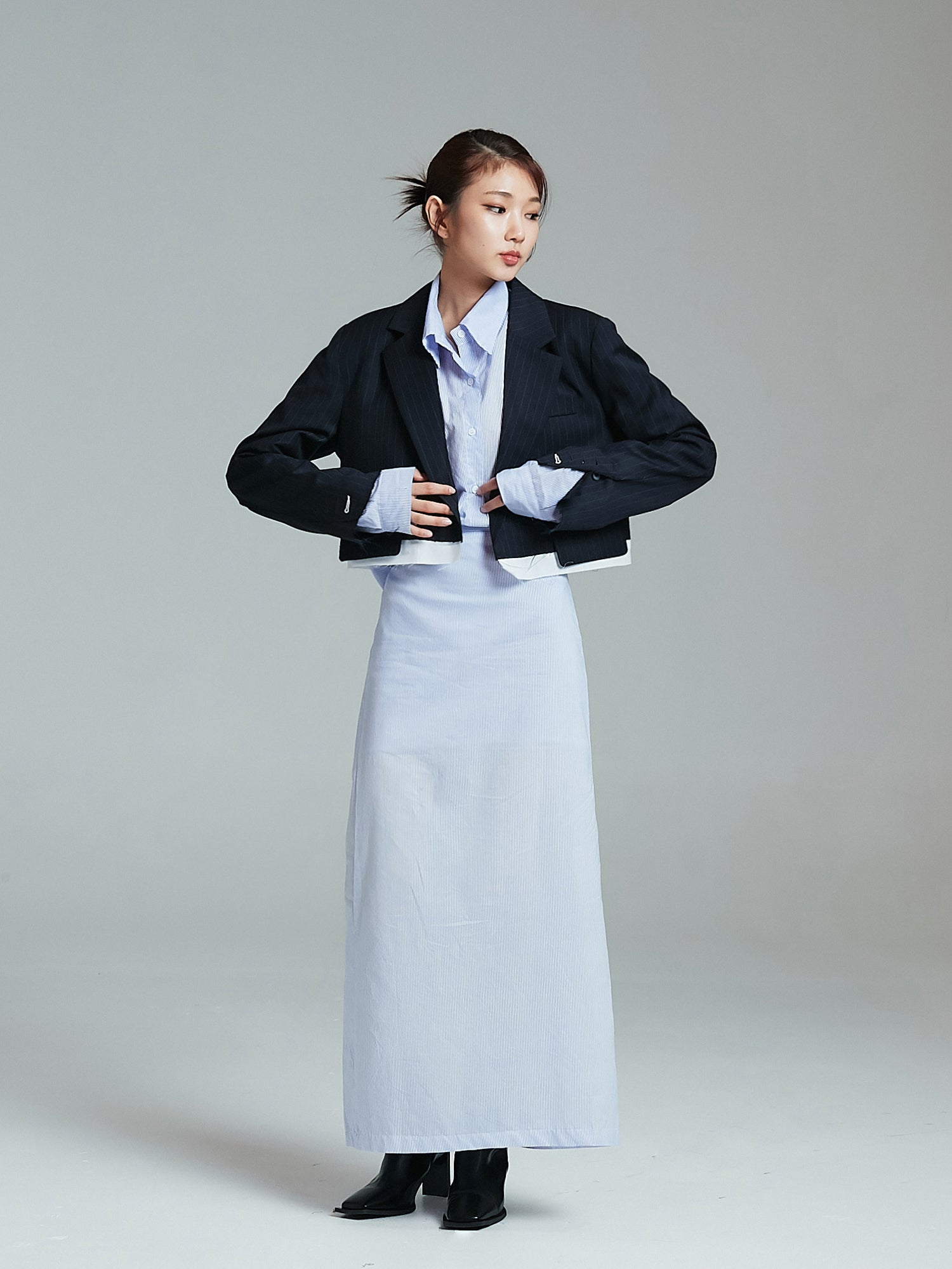 A full-length shot featuring the model wearing a slit maxi skirt paired with a blazer jacket, accentuating the chic essence of Korean street fashion.