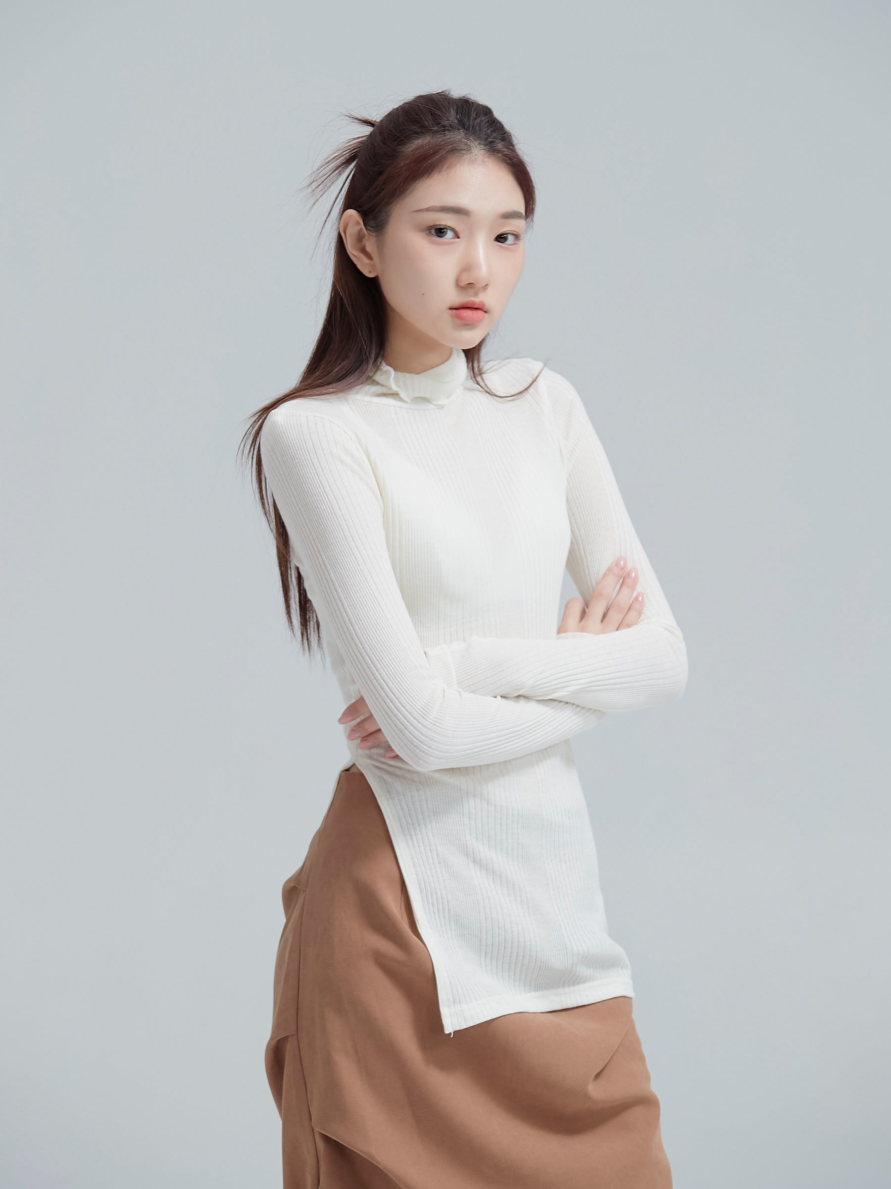 Side angle of the model showing its side slit of the ribbed neck top to showcase its feminine silhouette of the korean street fashion.