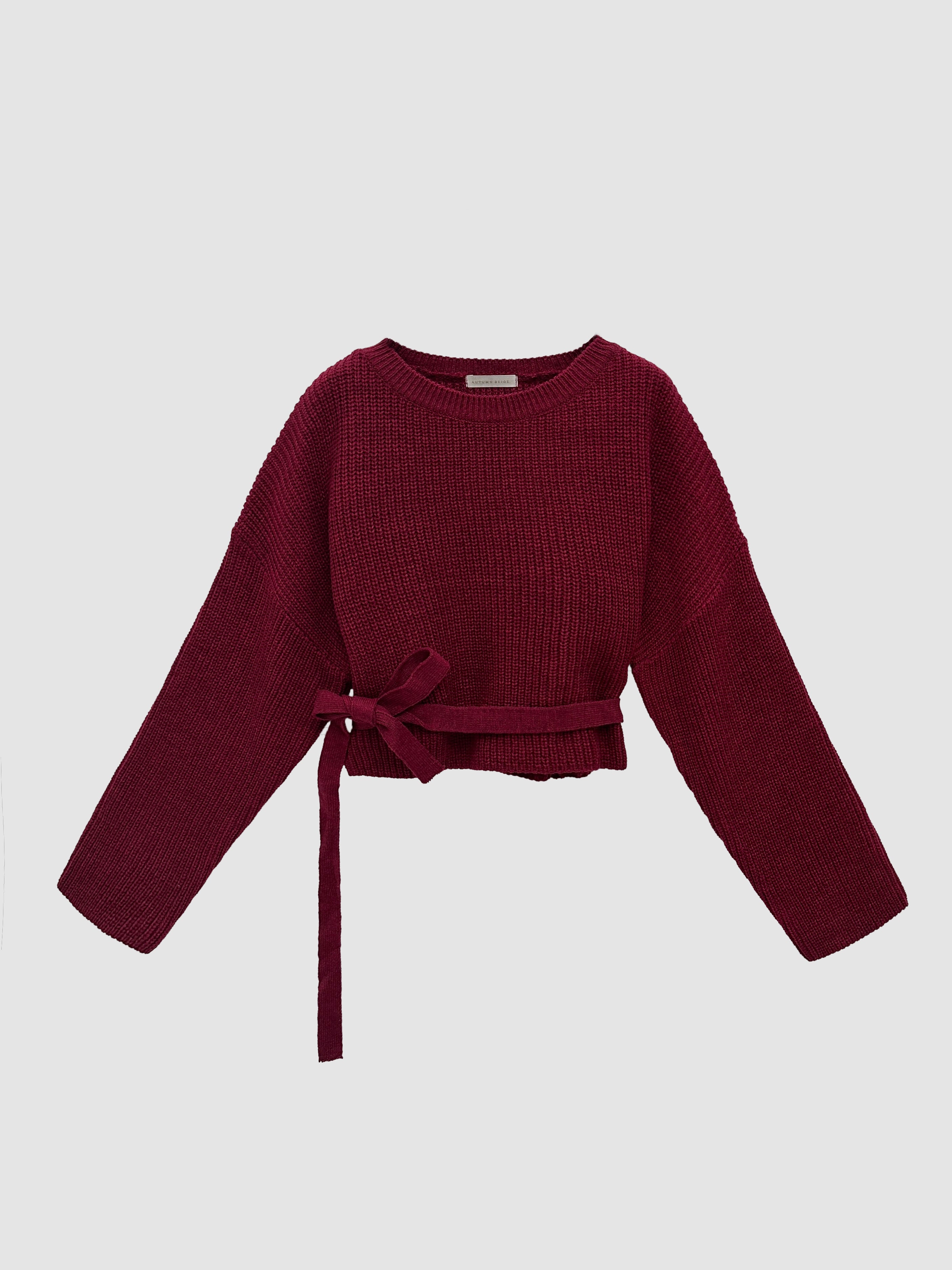 Provide a close-up front view of the red Sloane sweater, accentuating its waist strap detail that forms a ribbon-like feature.