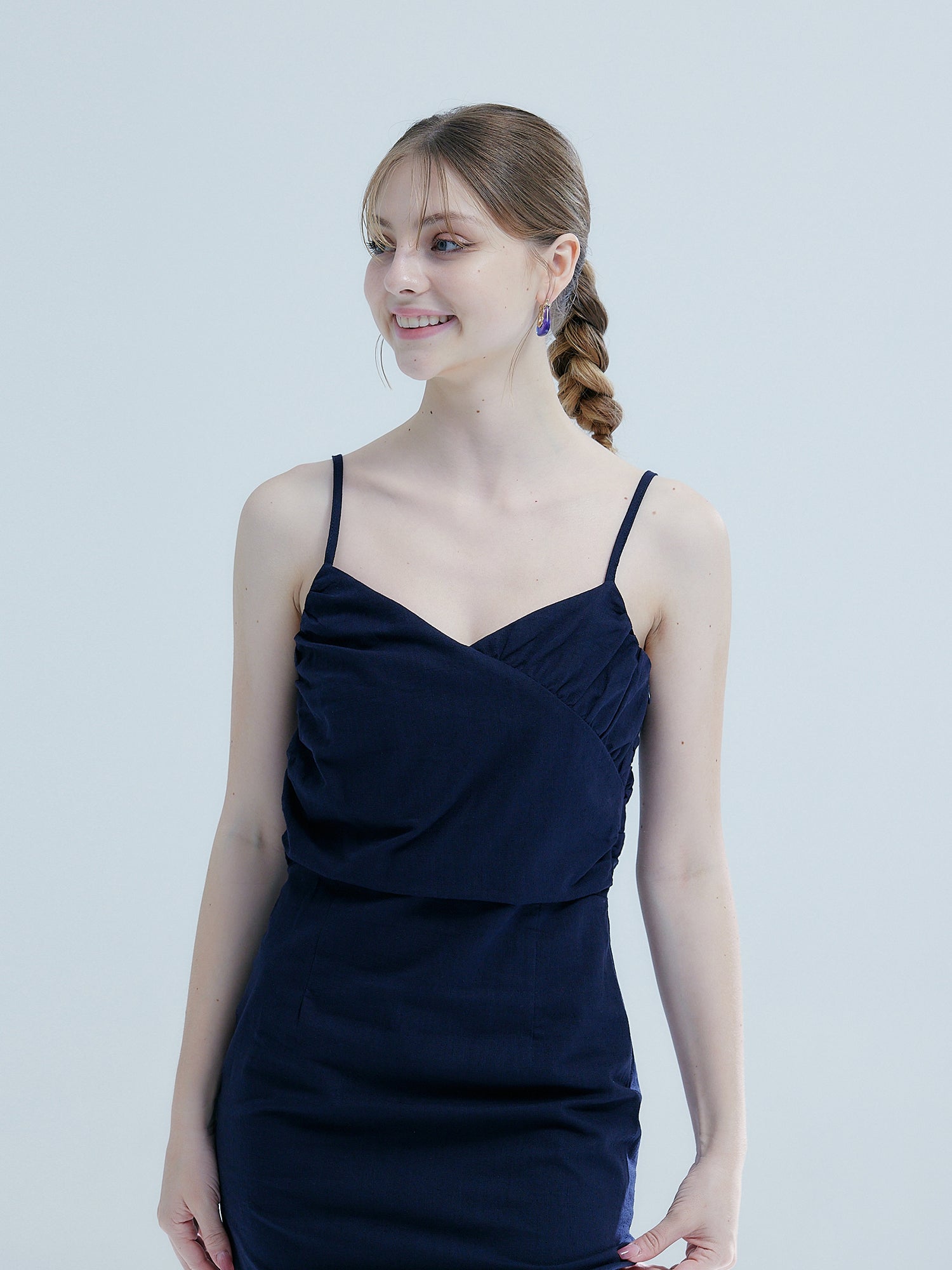 A close-up view of the model looking sideways wearing the navy smocked elastic dress.