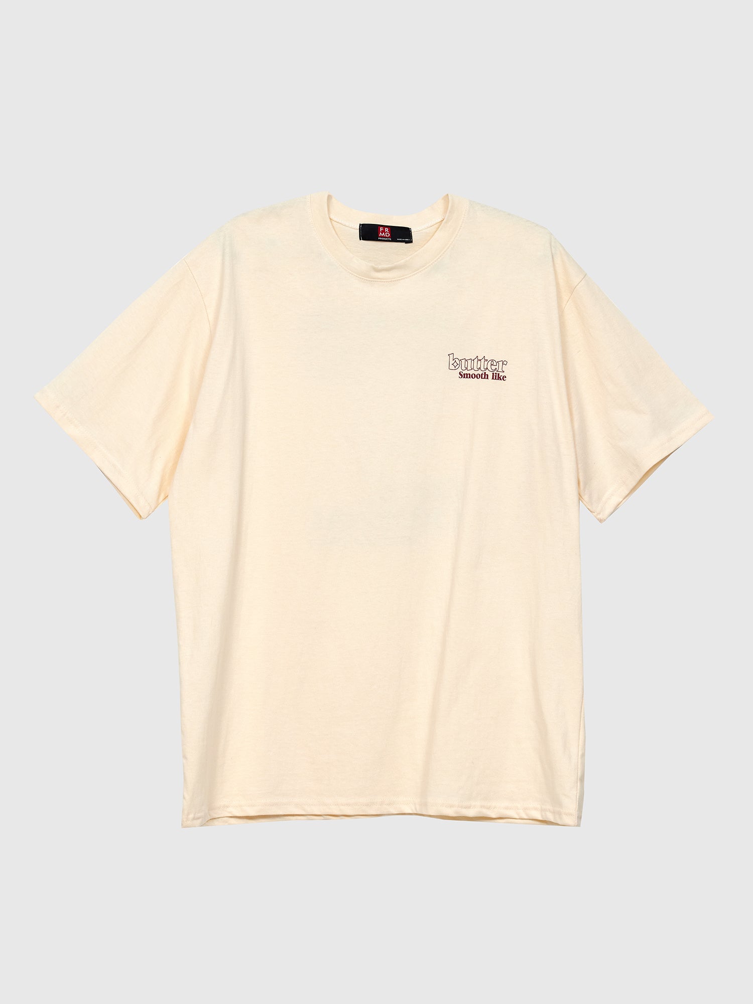 Front view of the light beige smooth like butter T-shirt with gray backdrop showcasing the front design of the shirt.