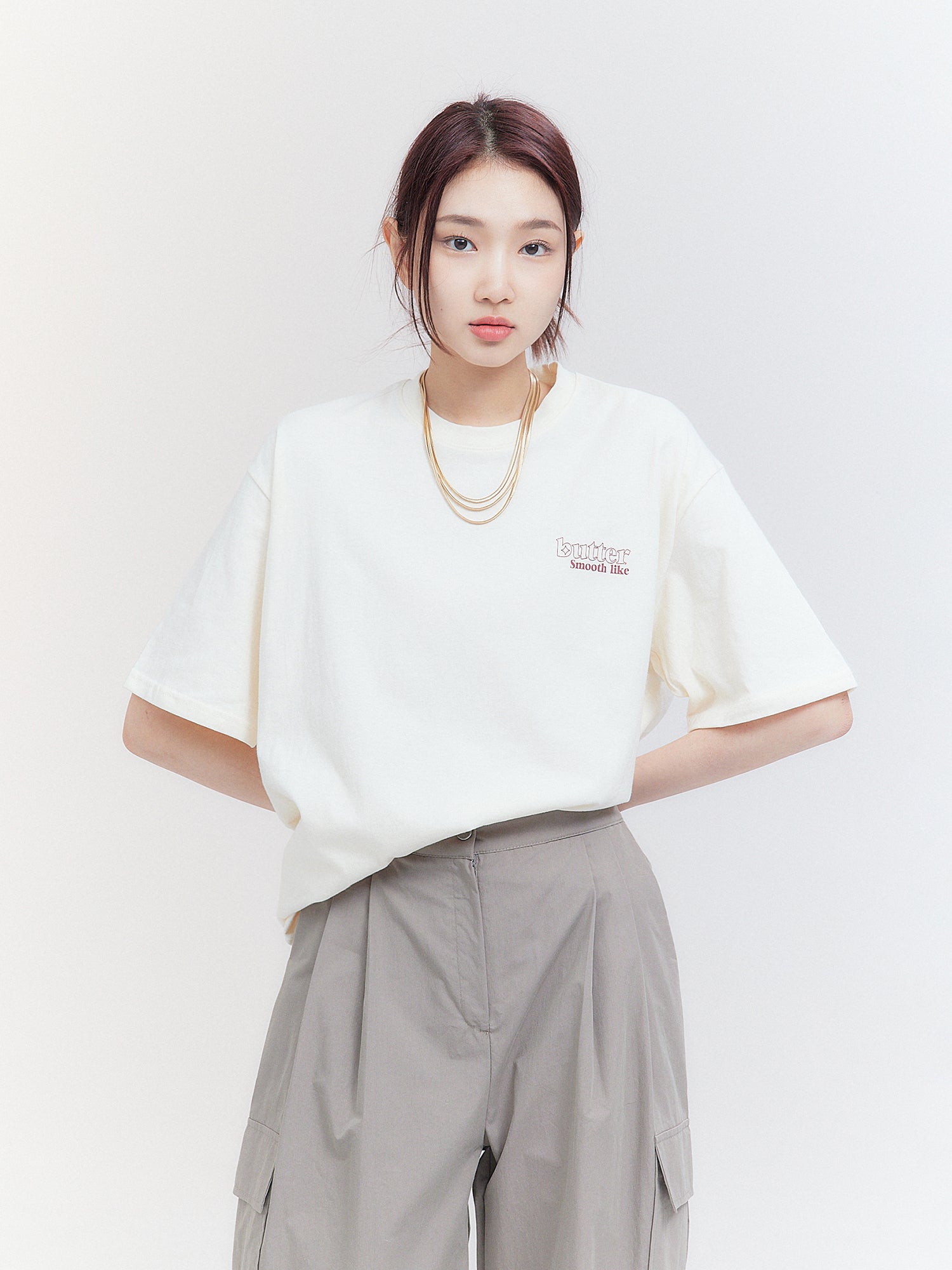 Showcasing Korean street fashion, a front view captures the model posing in the light beige 'Smooth Like Butter' T-shirt, radiating style and confidence.