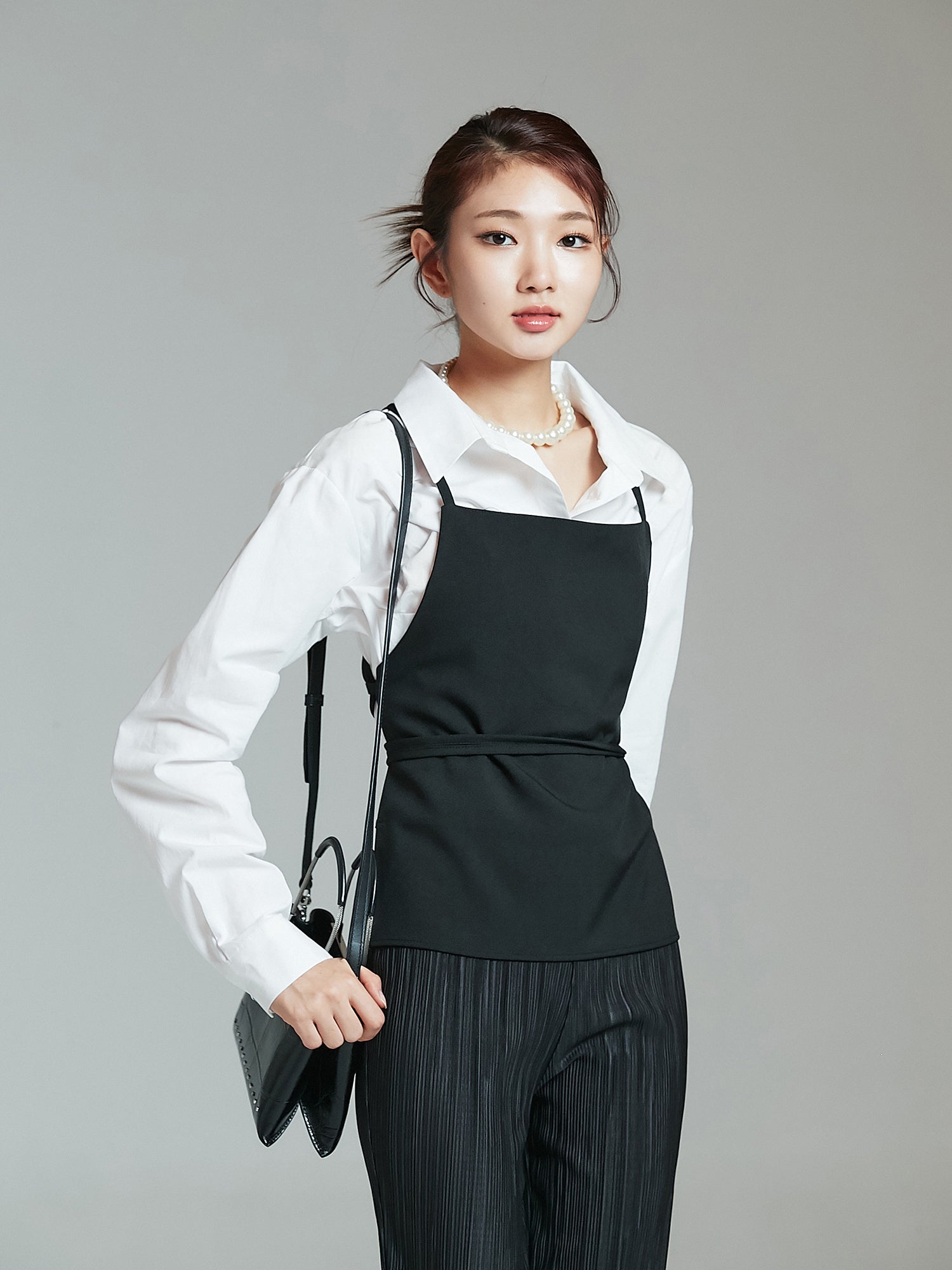 A tilted angle of the model wearing the strappy top showcasing its korean street fashion vibe.