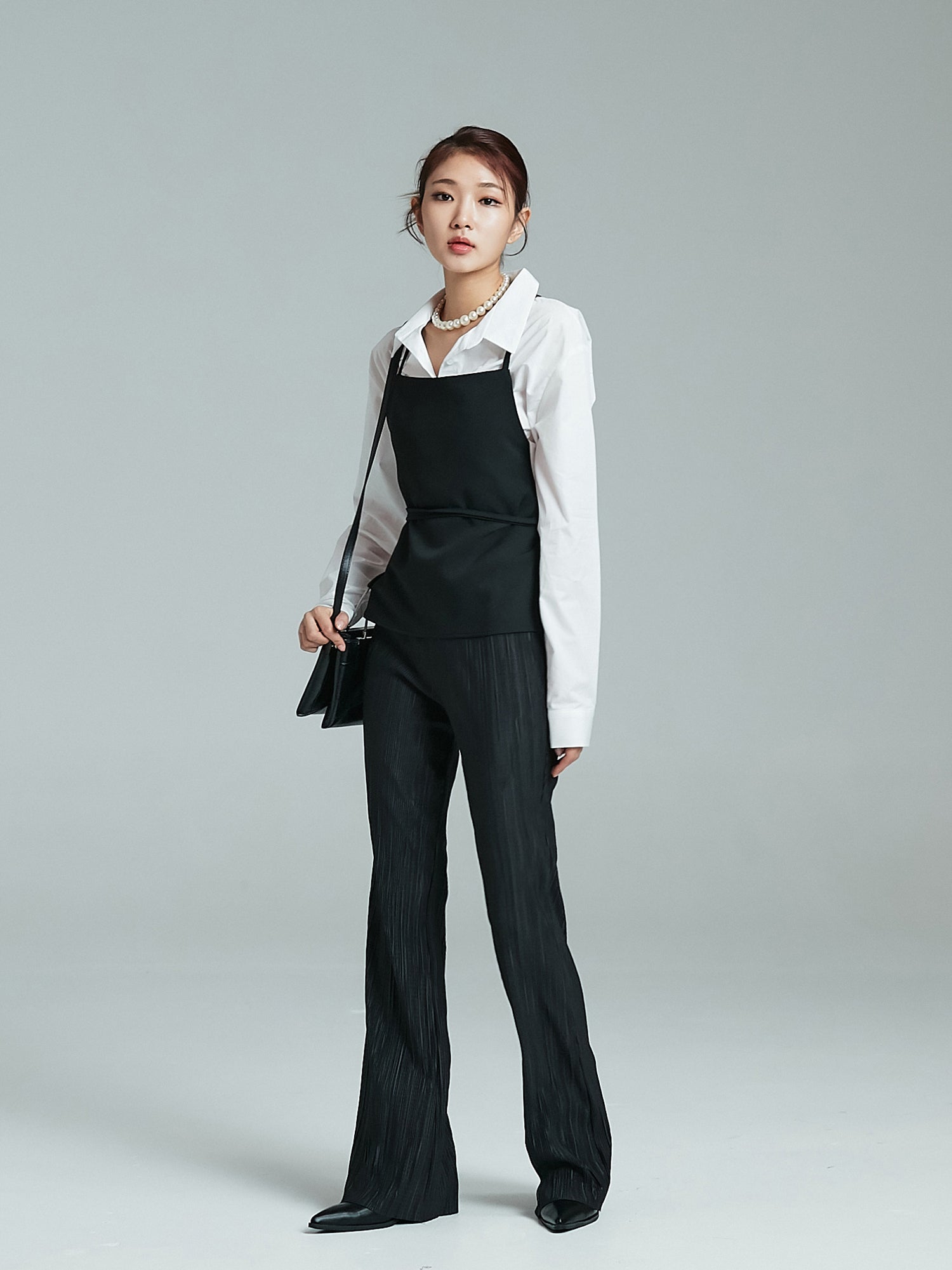 A tilted angle of the model wearing the black strappy top showcasing its korean street fashion vibe.