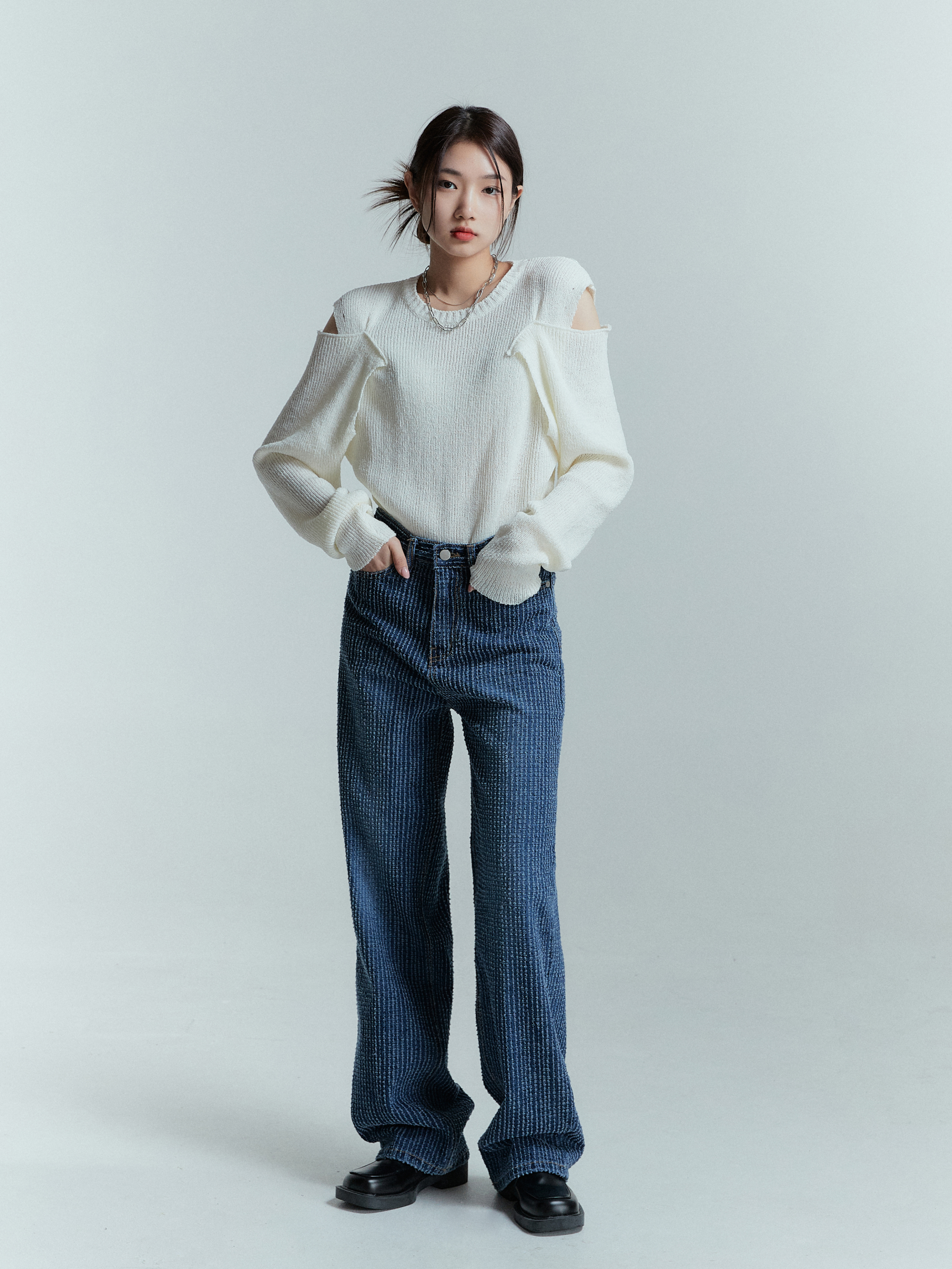 In a stylish standing pose, showcasing Korean street fashion, the model effortlessly rocks the striped jeans paired with an ivory sweater, creating a fashionable ensemble.