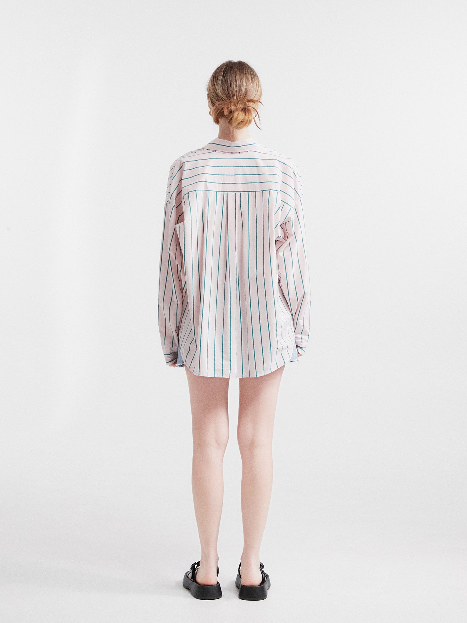 Offering a view from the back, capture the model wearing the striped loose shirt to showcase its flattering and well-fitted design.