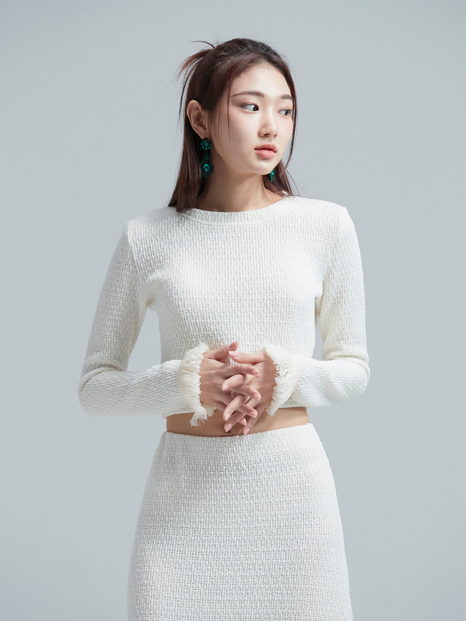 Zoom in on the model with hands gracefully clasped, emphasizing the intricate designs on the cuffs and showcasing the refined Korean aesthetic outfit.