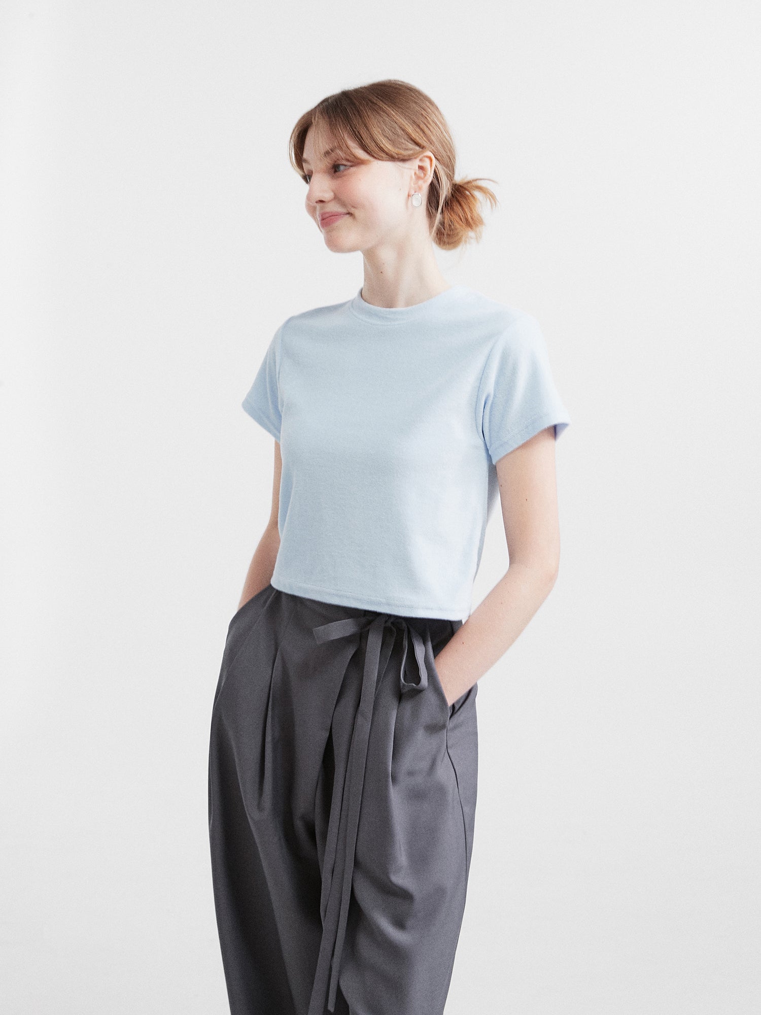 A side-angle of a model wearing the light blue crewneck top showing the side fitting of the top.