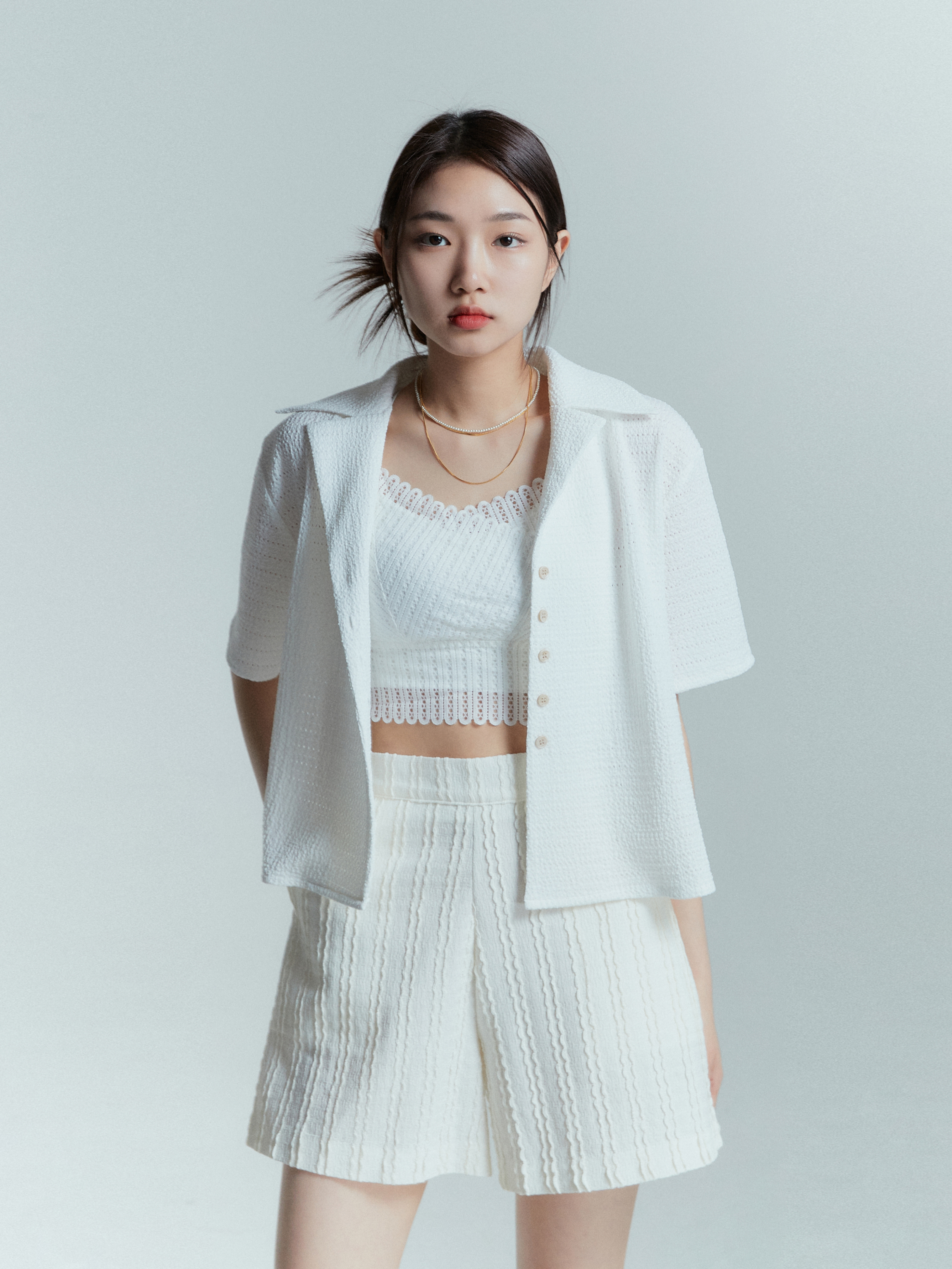 In a medium shot, a model with a Korean aesthetic outfit faces the camera while wearing the textured shorts, allowing for a closer view of the intricate texture design.