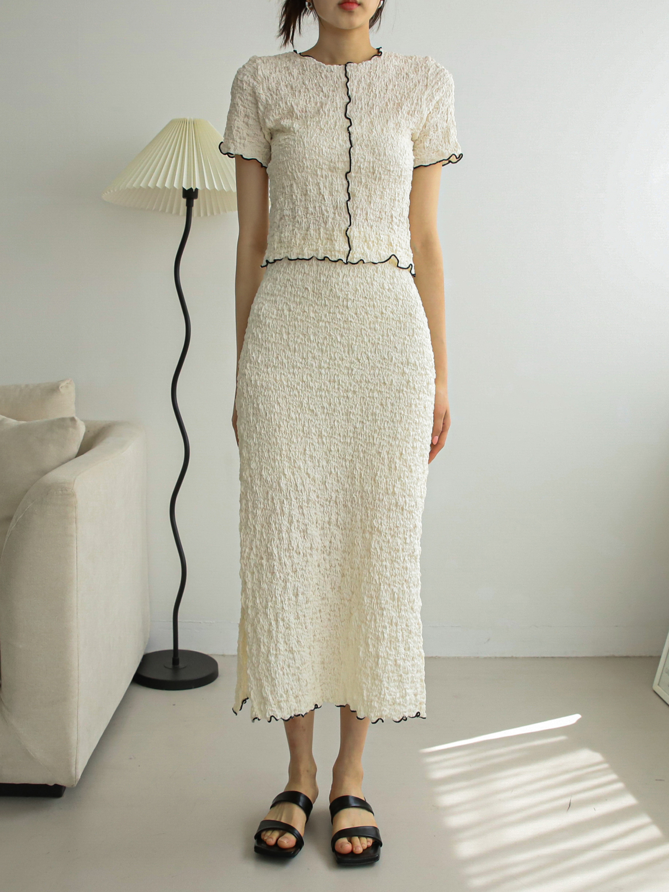 Head-to-toe shot of a model wearing the cream textured top to showcase the front design.