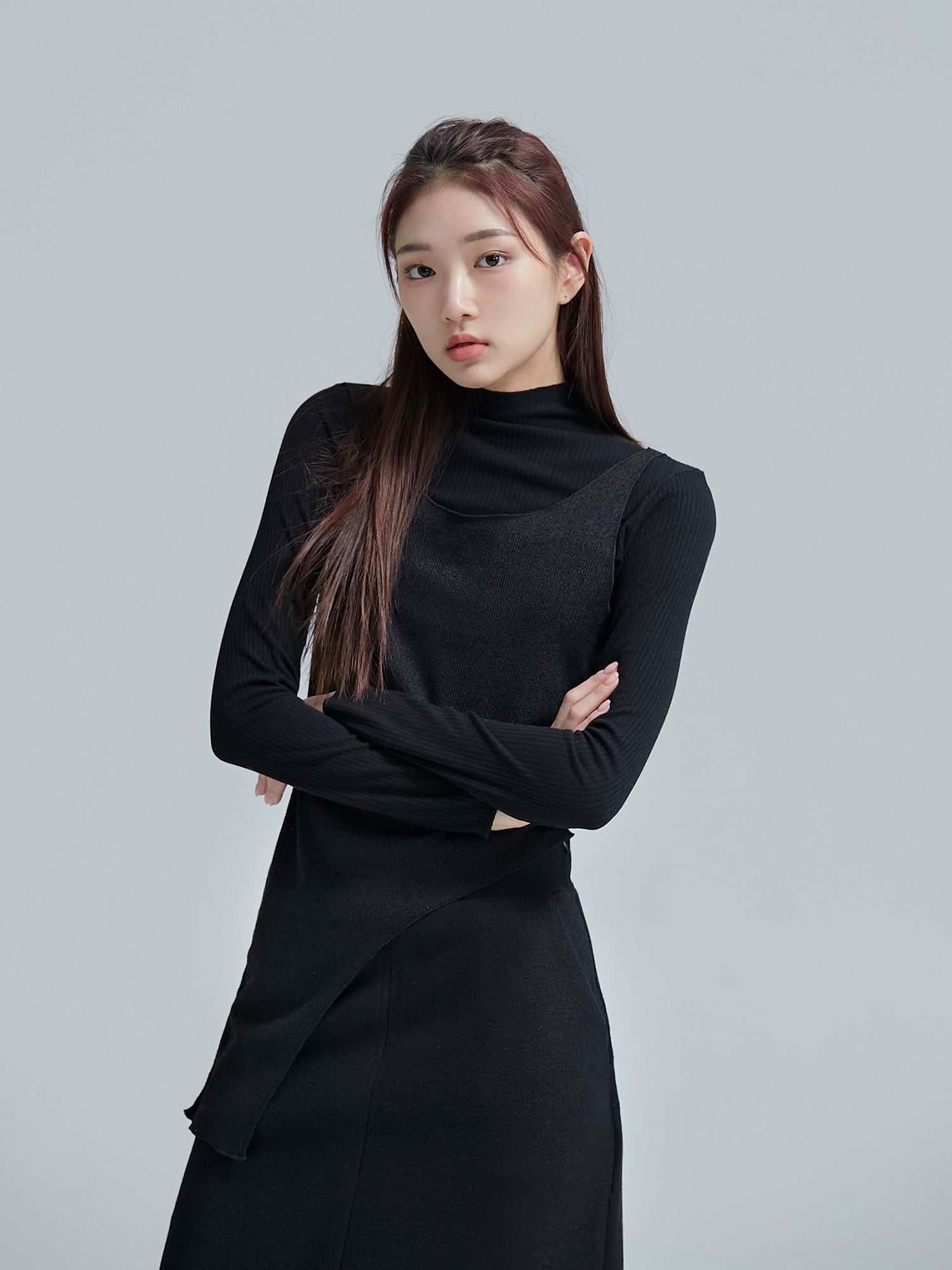 Front view of the model posing while wearing the turtleneck sleeveless top to show its uniquely detail designs.