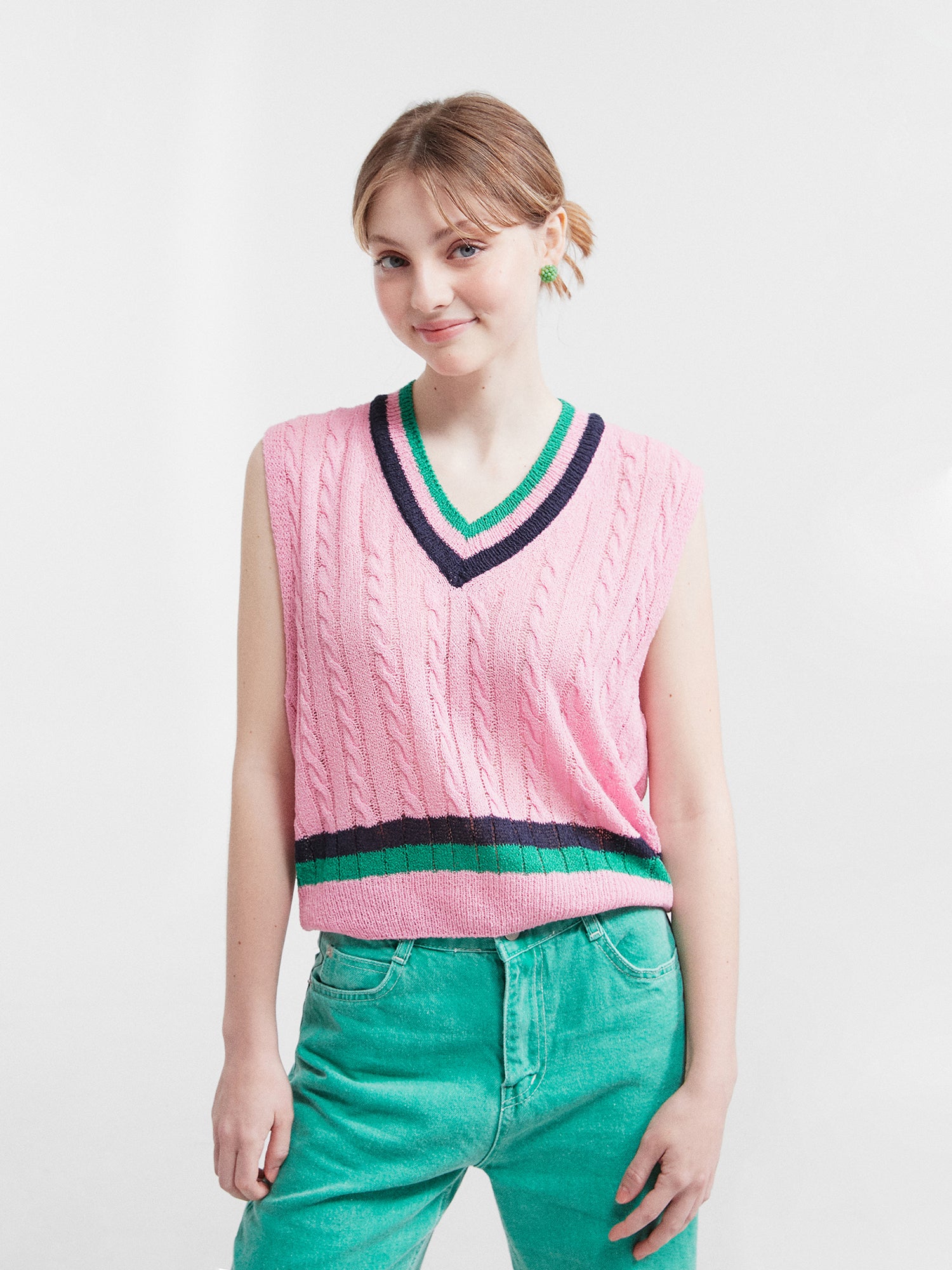 A close-up front view of the model wearing the pink V-neck knit vest.