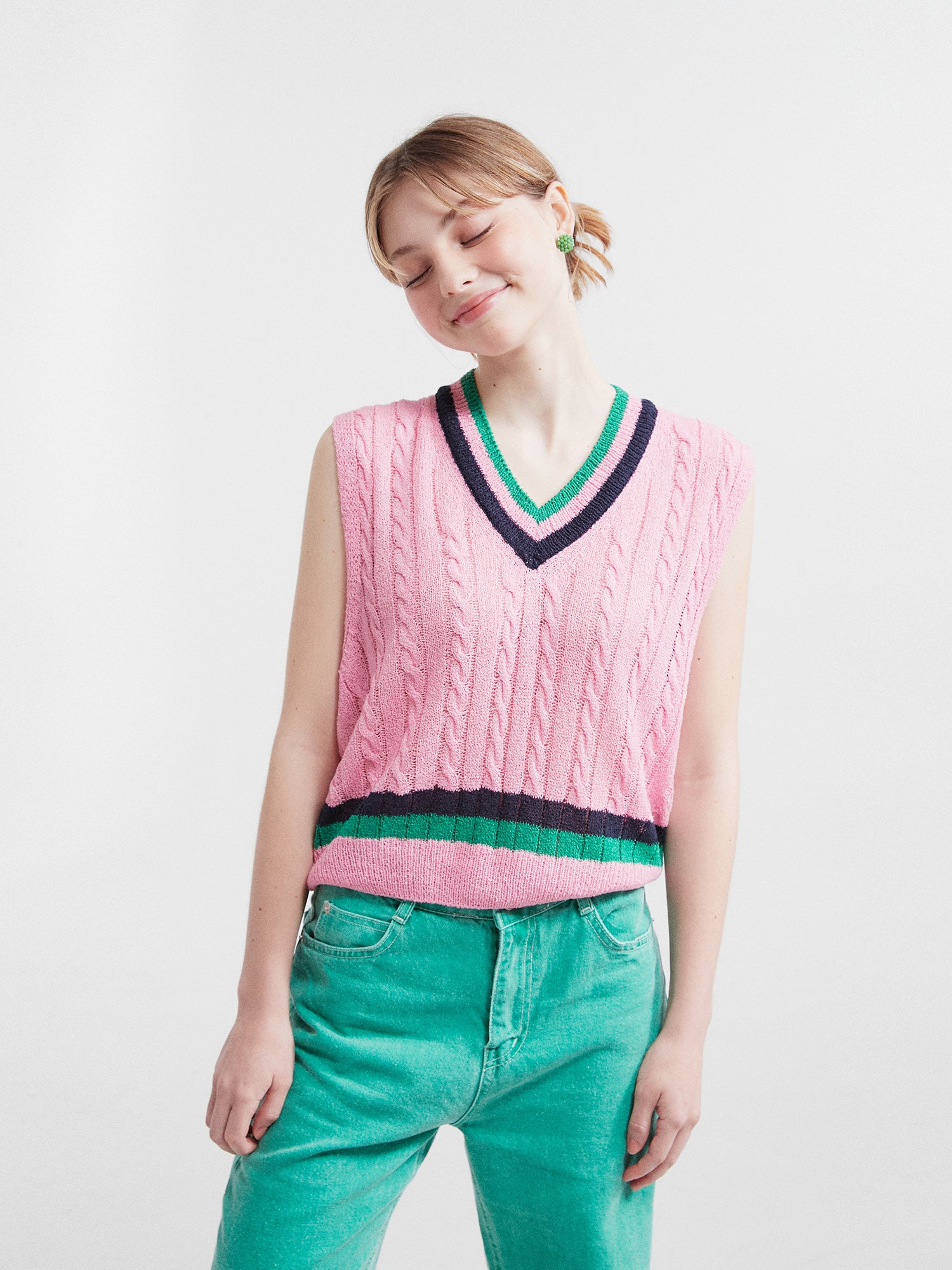 Front view of the model her head tilted to the side wearing the pink V-neck knit vest