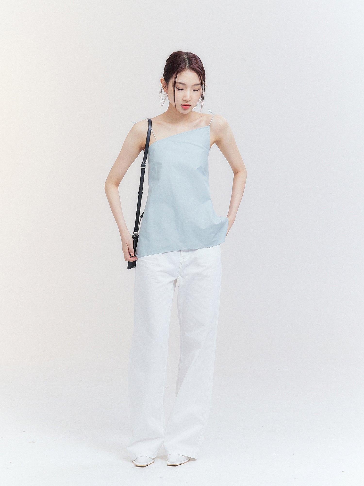 Front shot of the model wearing the white wide leg denim jeans matching it with mint asymmetric cami top.