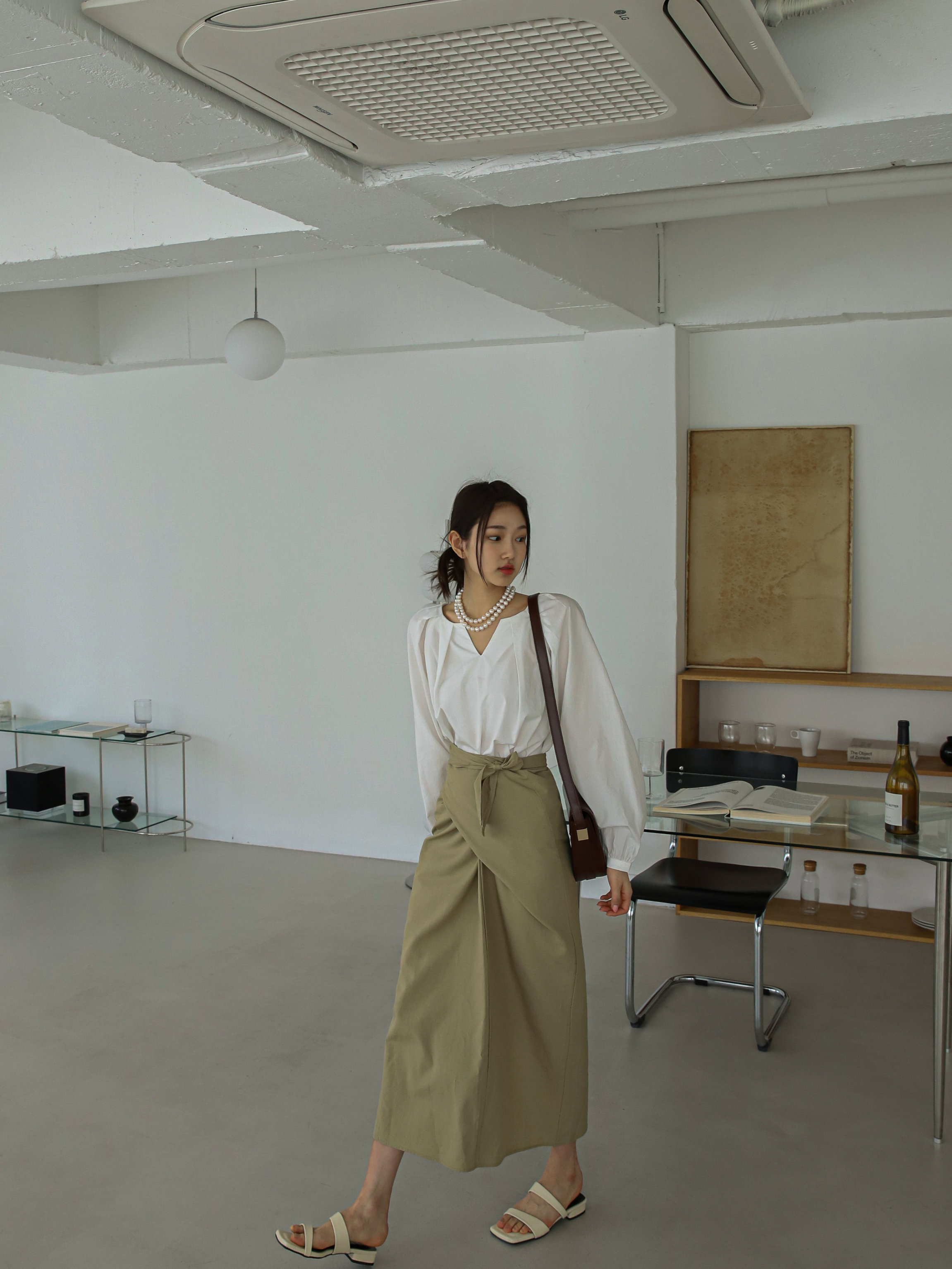 Witness the model gracefully strolling in the beige wrap midi skirt, flawlessly paired with a white raglan sleeve blouse.