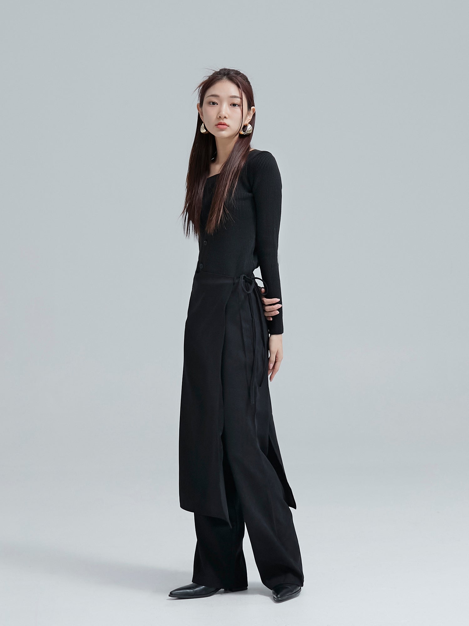 A side-angle shot showcasing the model in wrap skirt pants, highlighting the intricate wrap tied with pants underneath design.