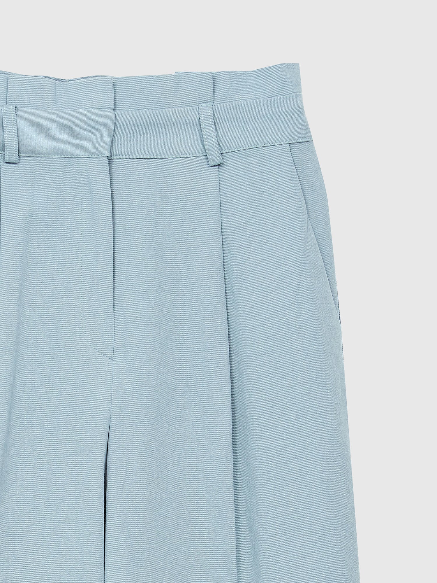 A zoomed-in shot of the light blue pleated pants highlighting the belted and pleated detail of the pants.