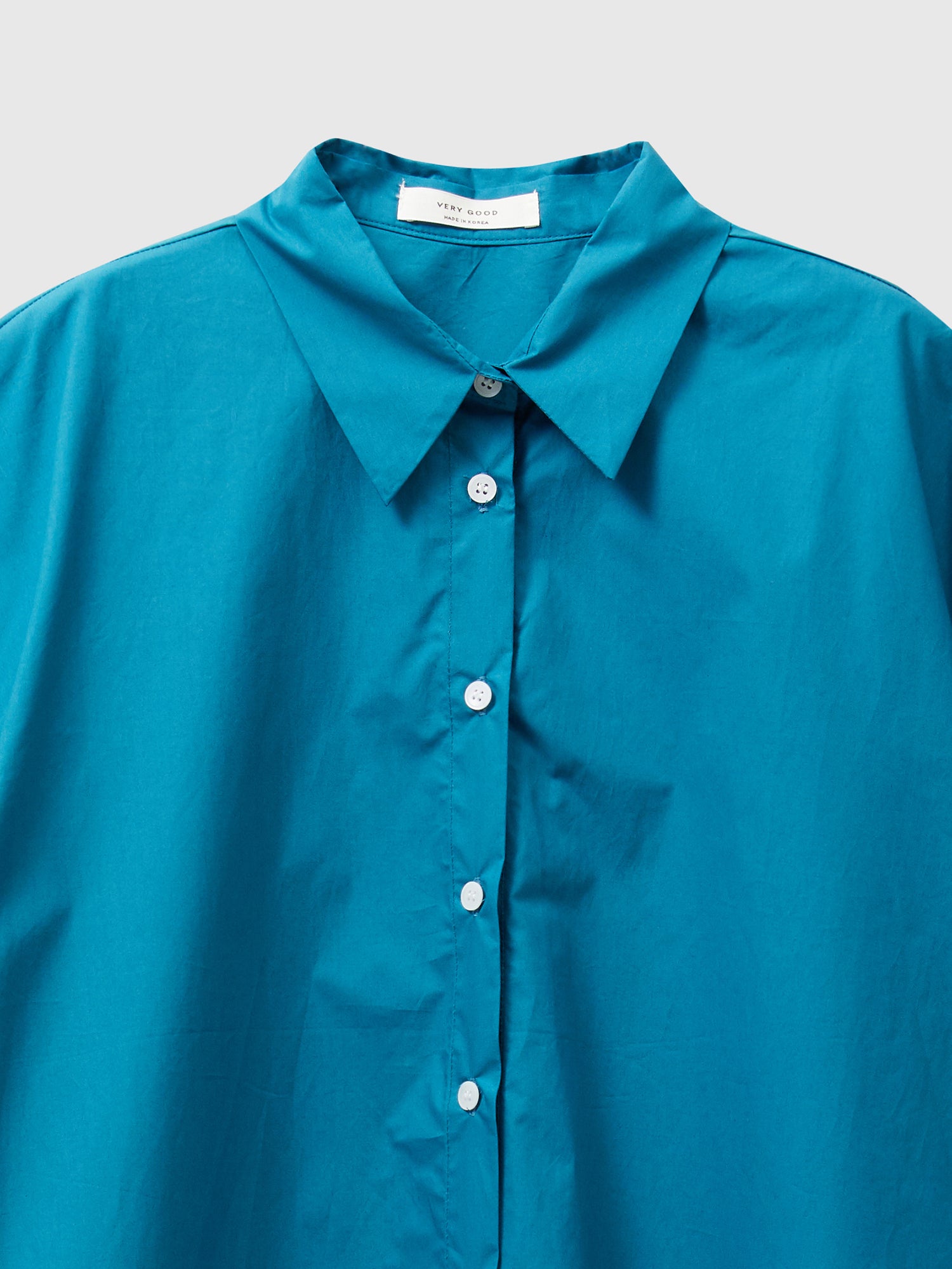 A zoomed-in shot of a button front shirt highlighting the pointed collars and buttons in exquisite detail.