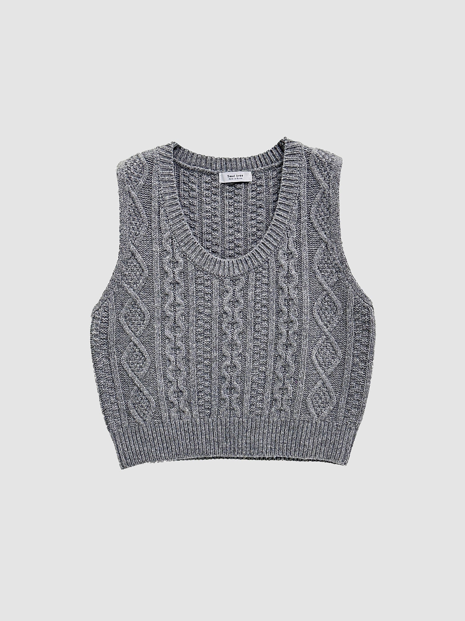 Product detailed shot of the gray cable knit vest with gray backdrop.