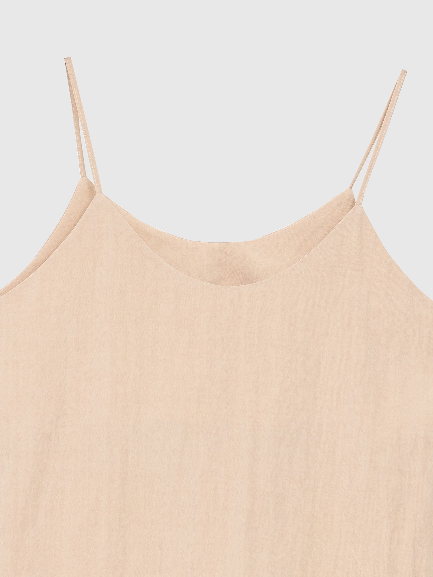 Zoomed-in view of the beige cami top showing the neckline and fabric texture of the top.